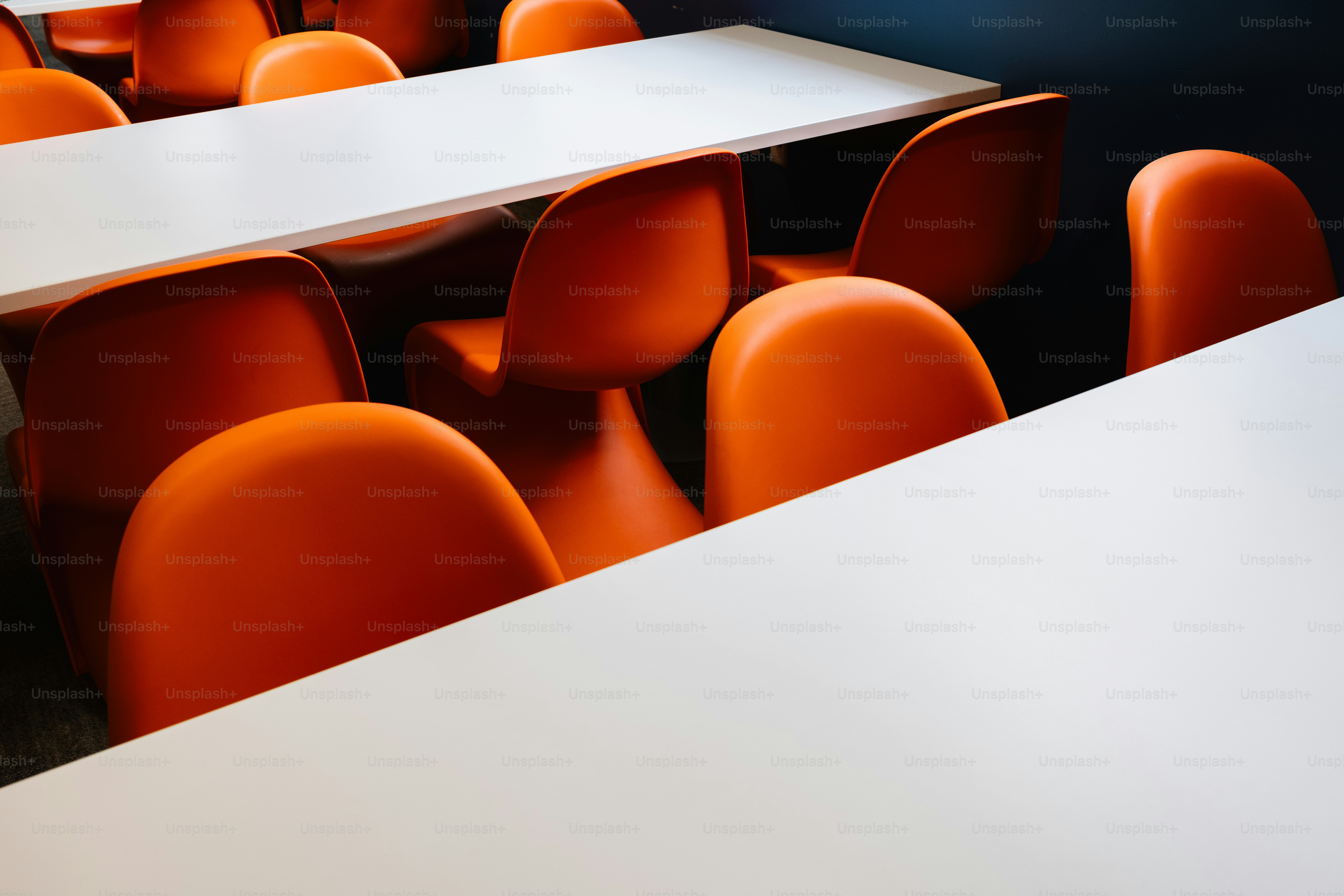 Orange chairs surround white tables in a classroom.