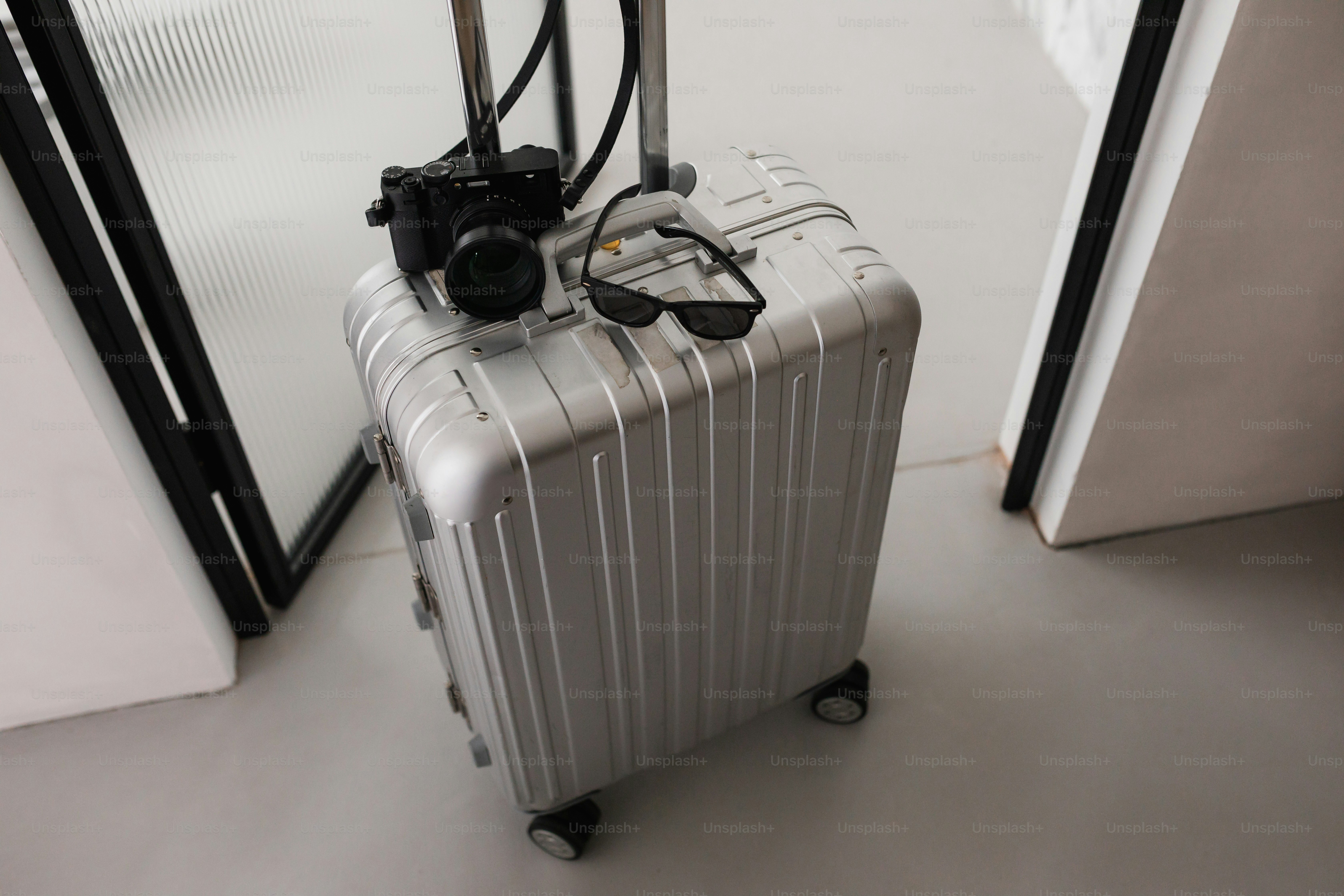 Suitcase, camera, and glasses ready for travel.