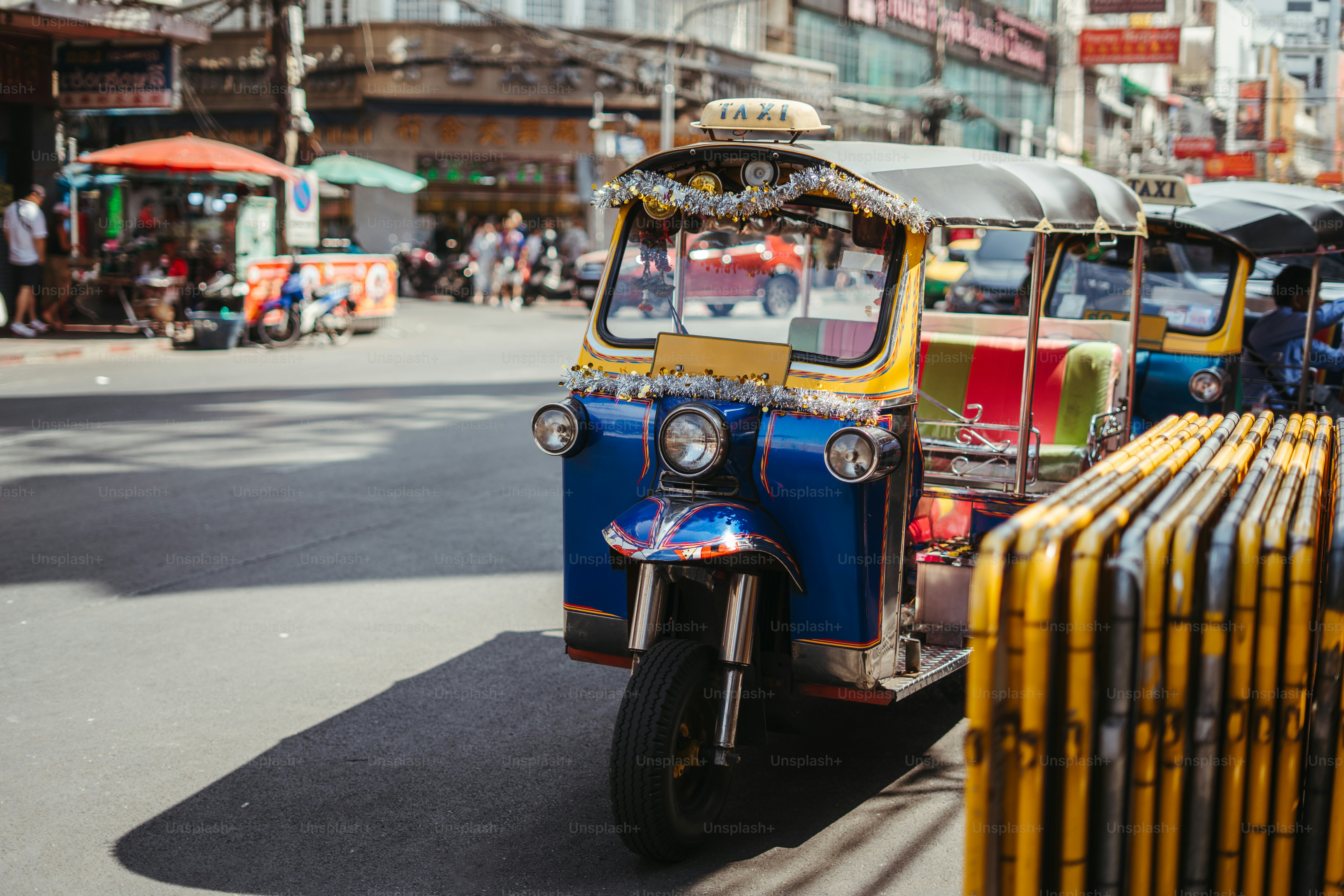 Tuk-tuks are parked on a busy city street.