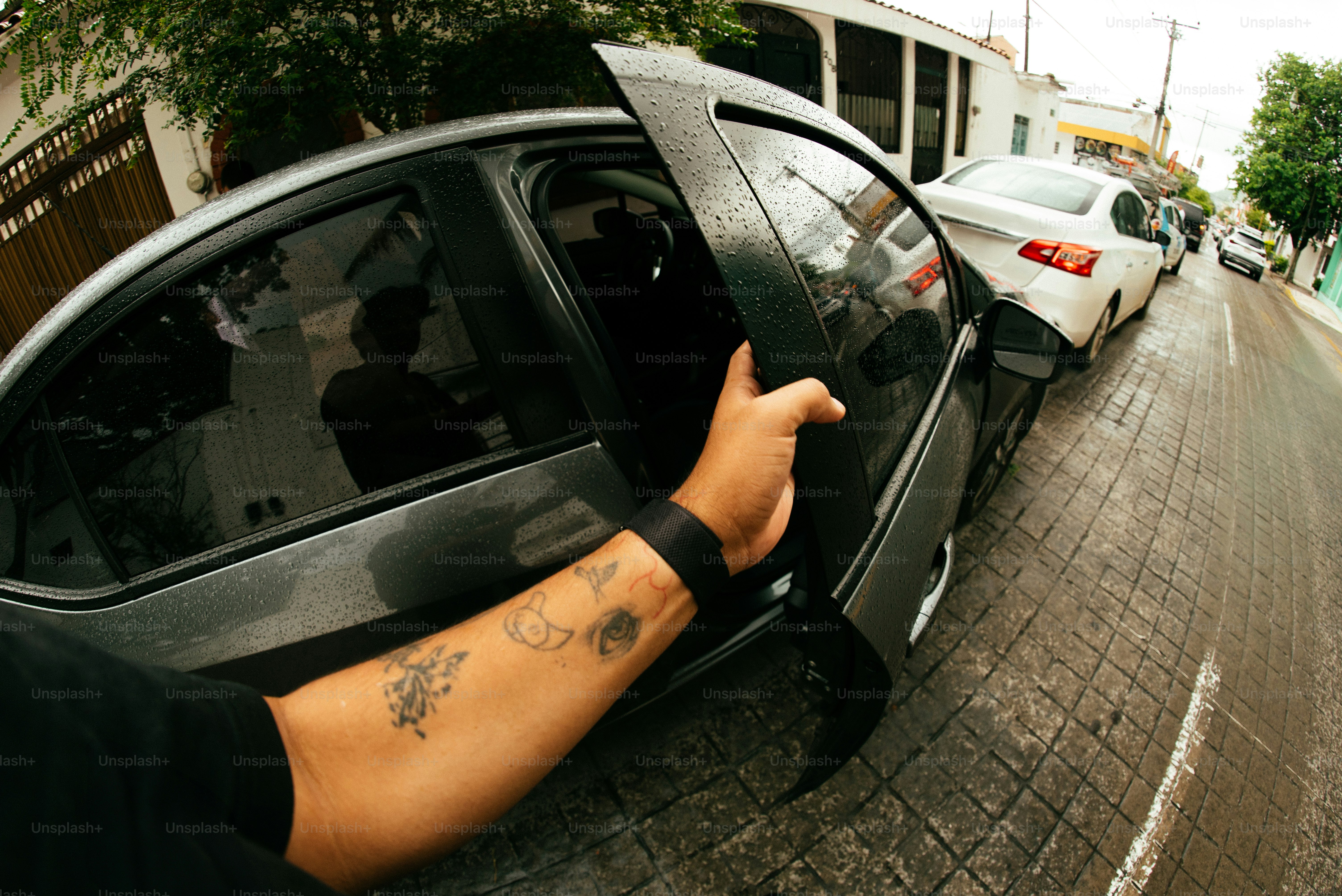 A person opens a car door on a street.
