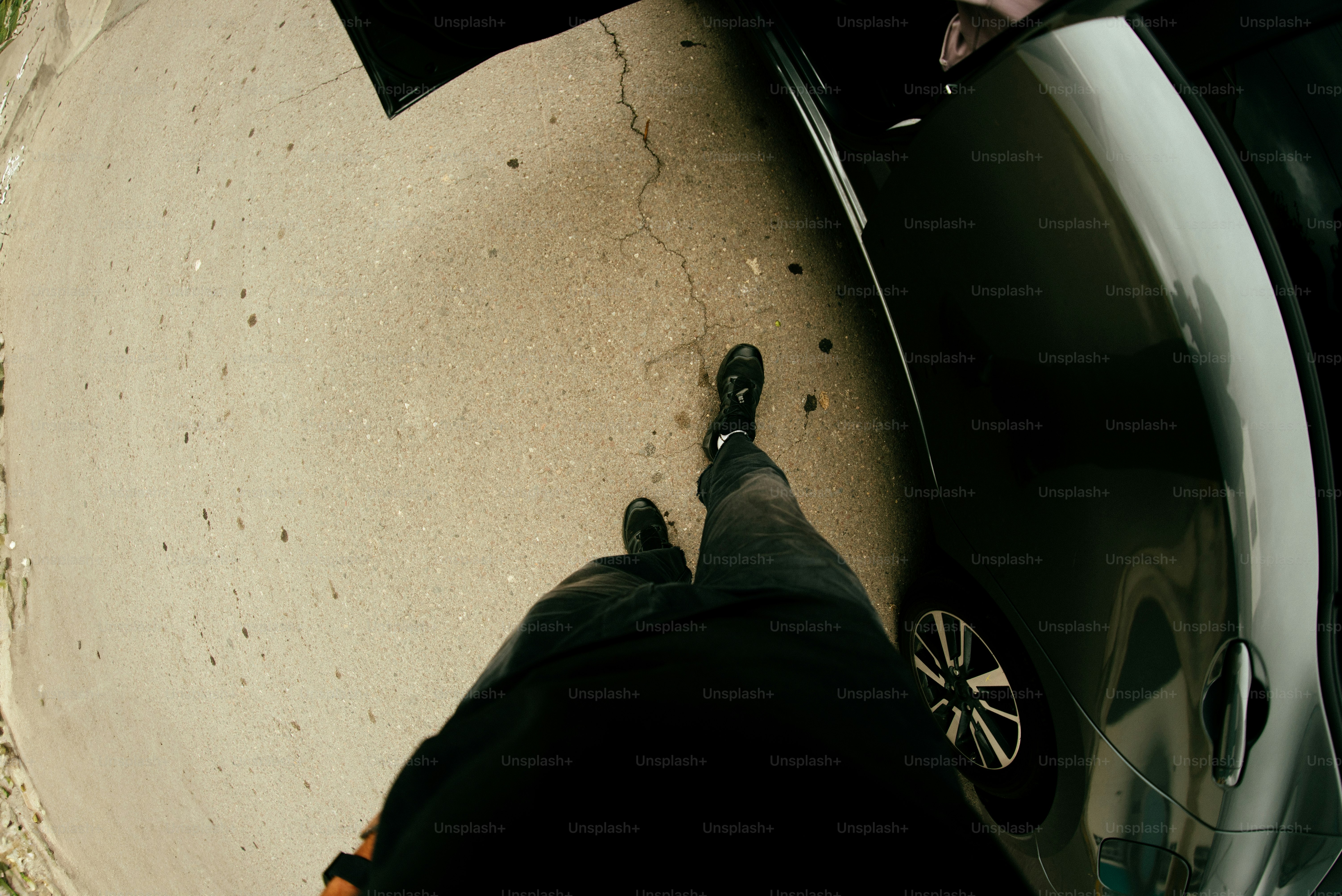 Person exits a car onto a concrete surface.