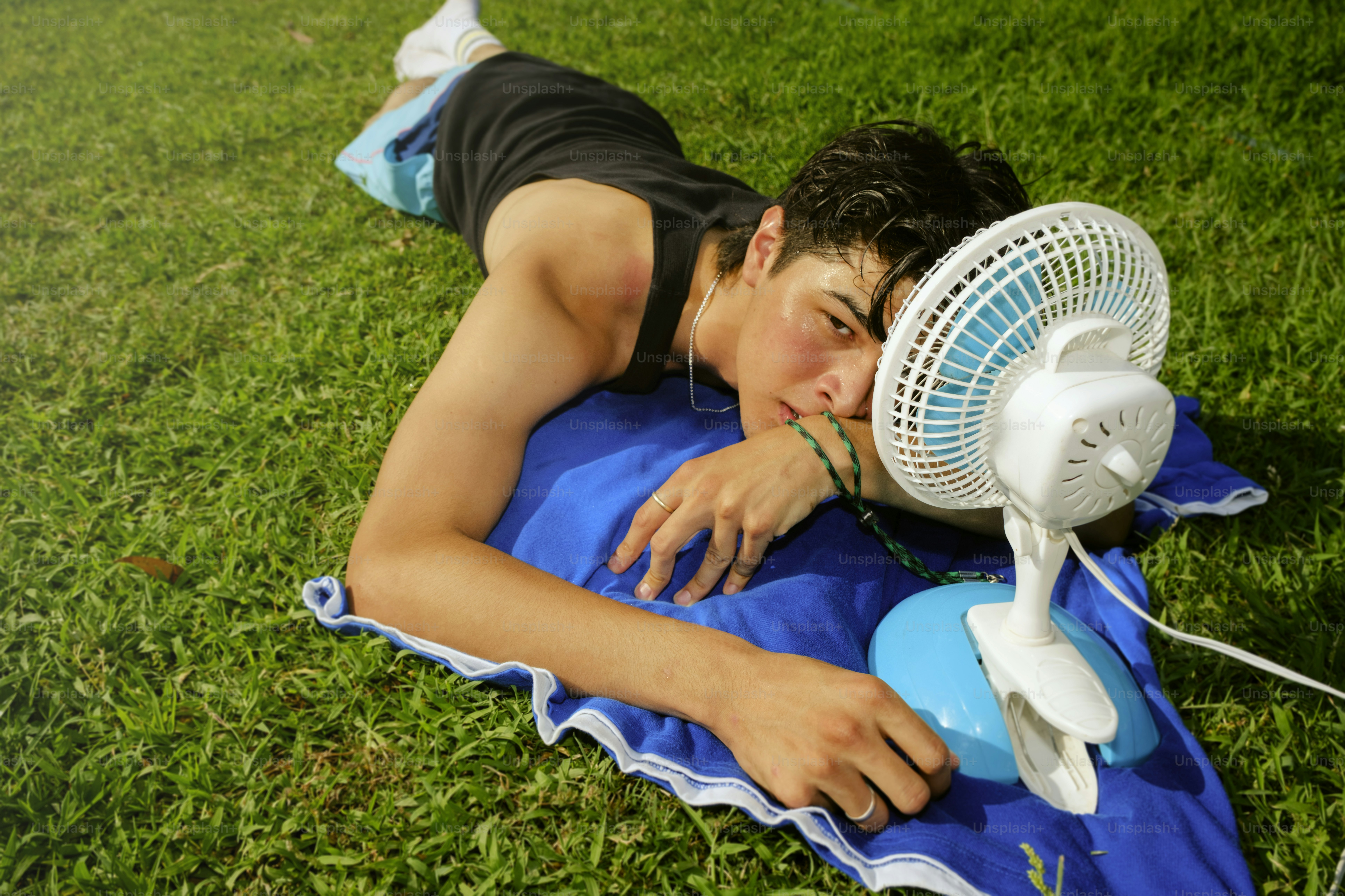 L'uomo si rilassa al sole con un ventilatore portatile.