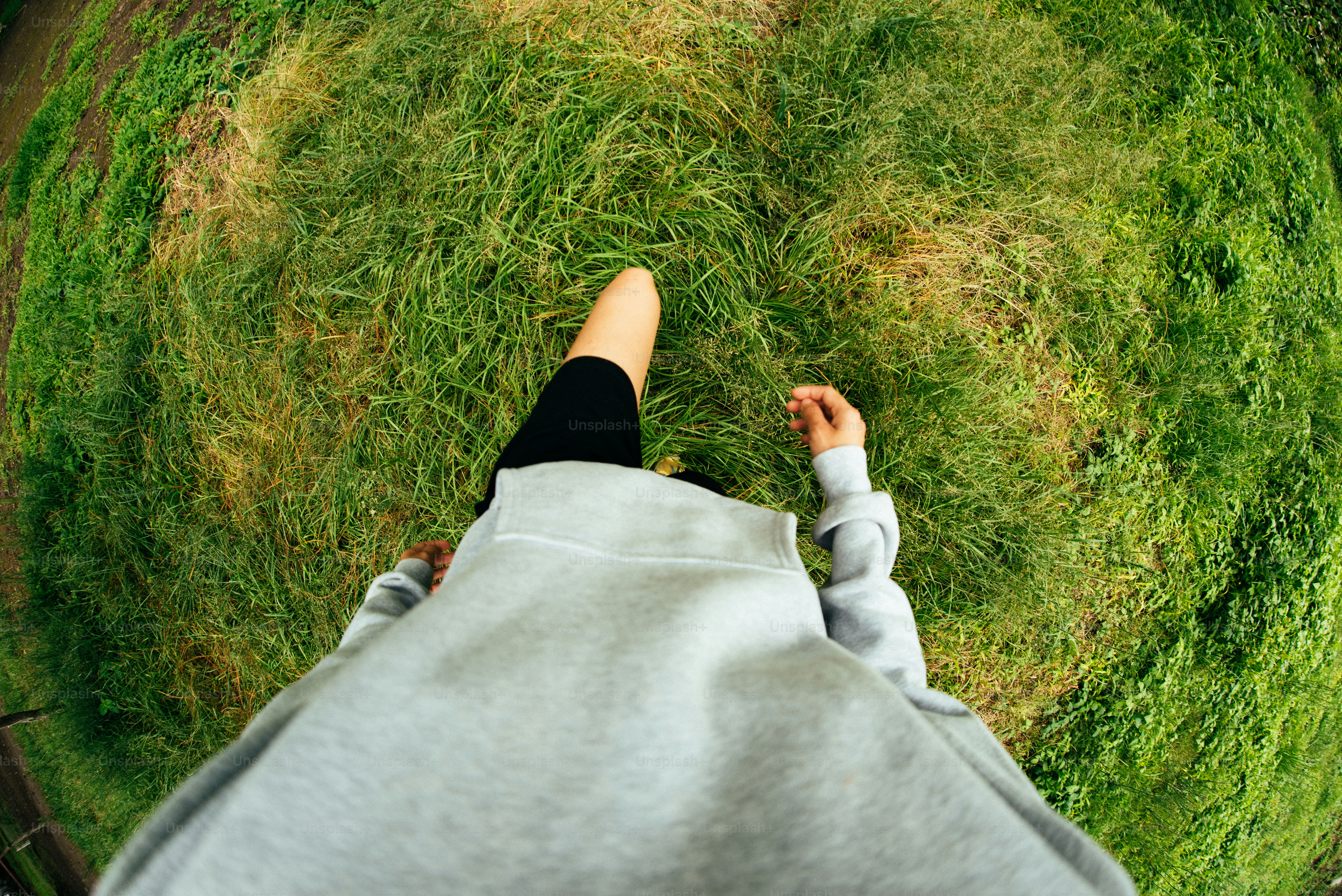 Person walking on green grass from a fisheye perspective.