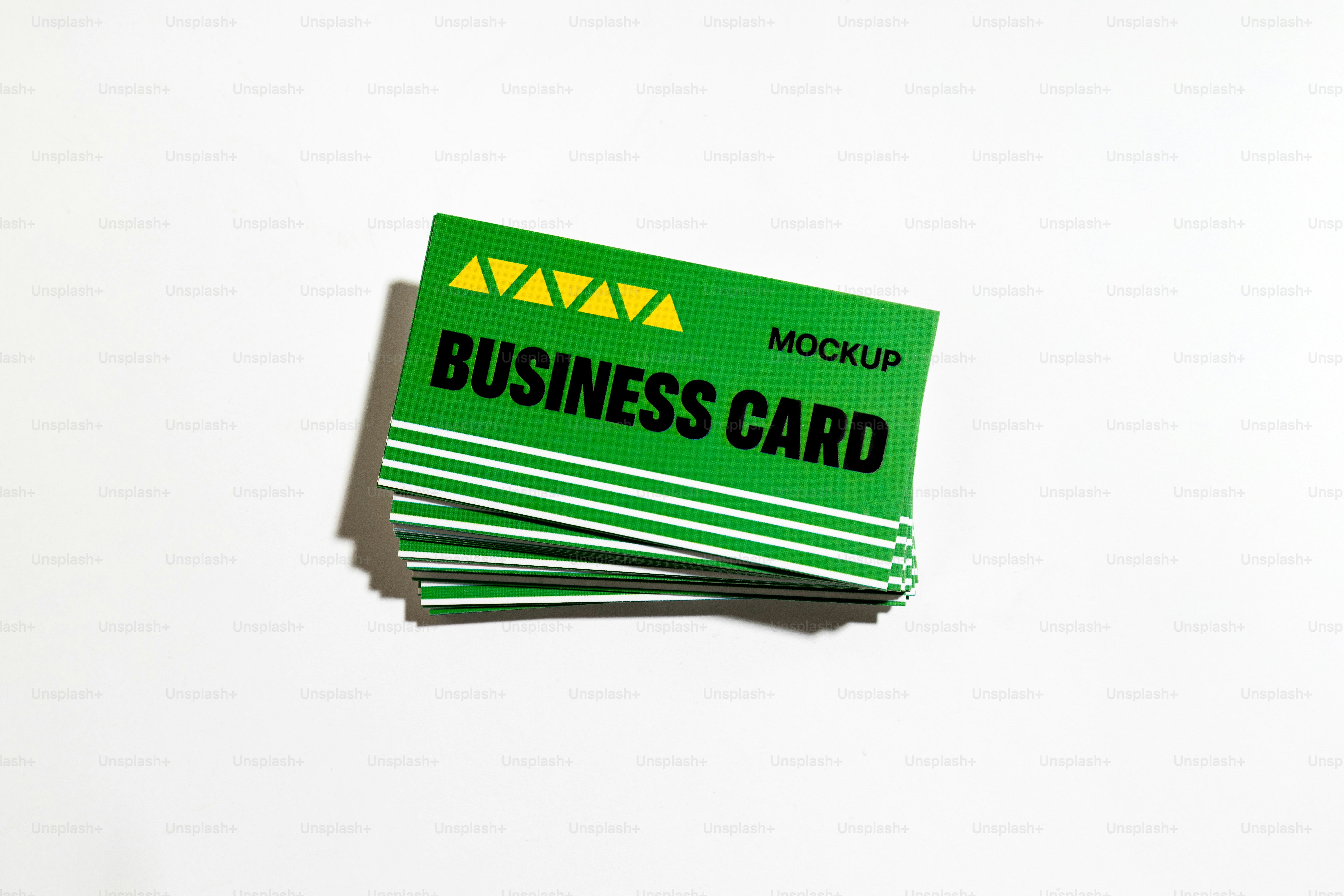 Green business card mockups are stacked on a white surface.