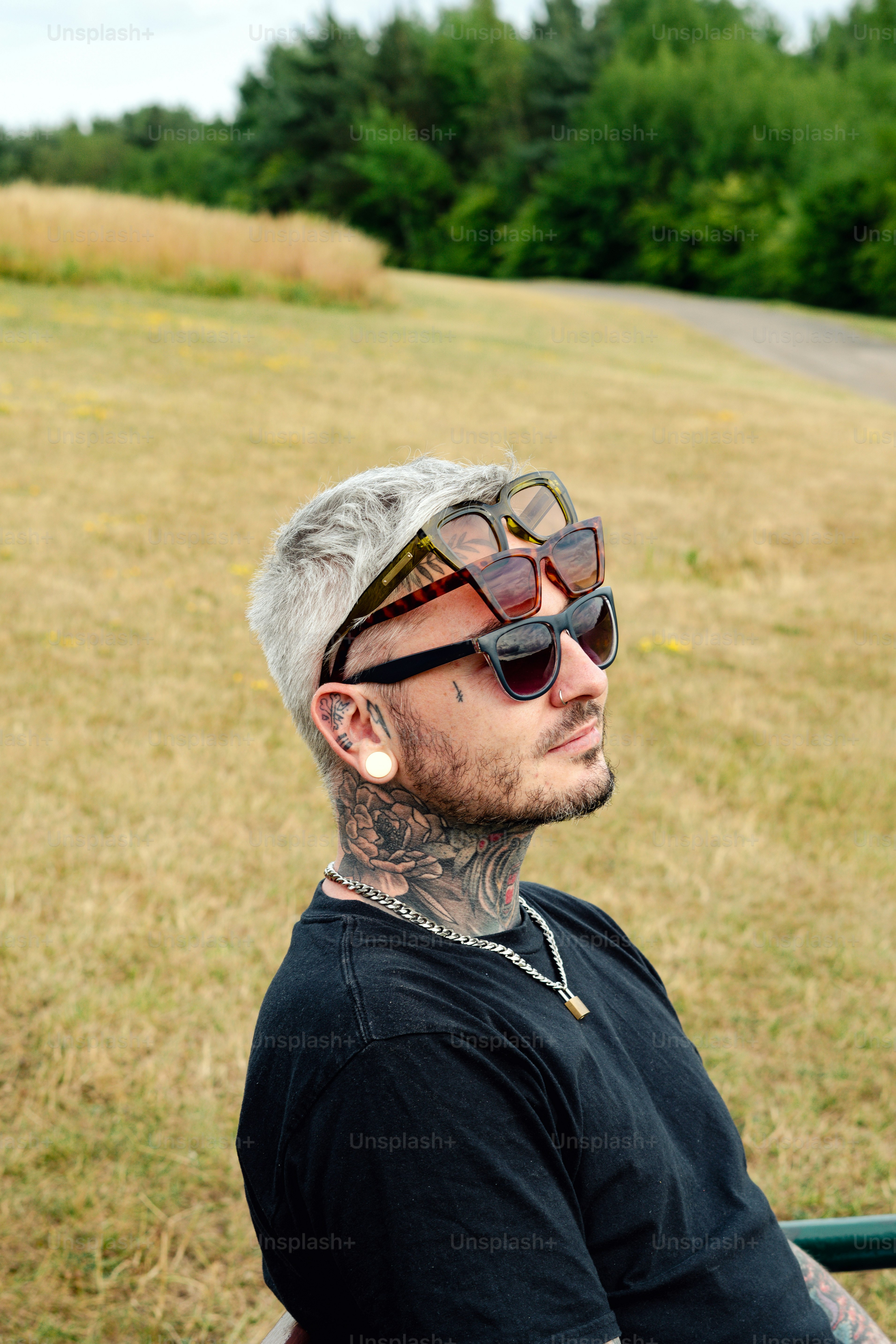 Man wears sunglasses on his head in a park.