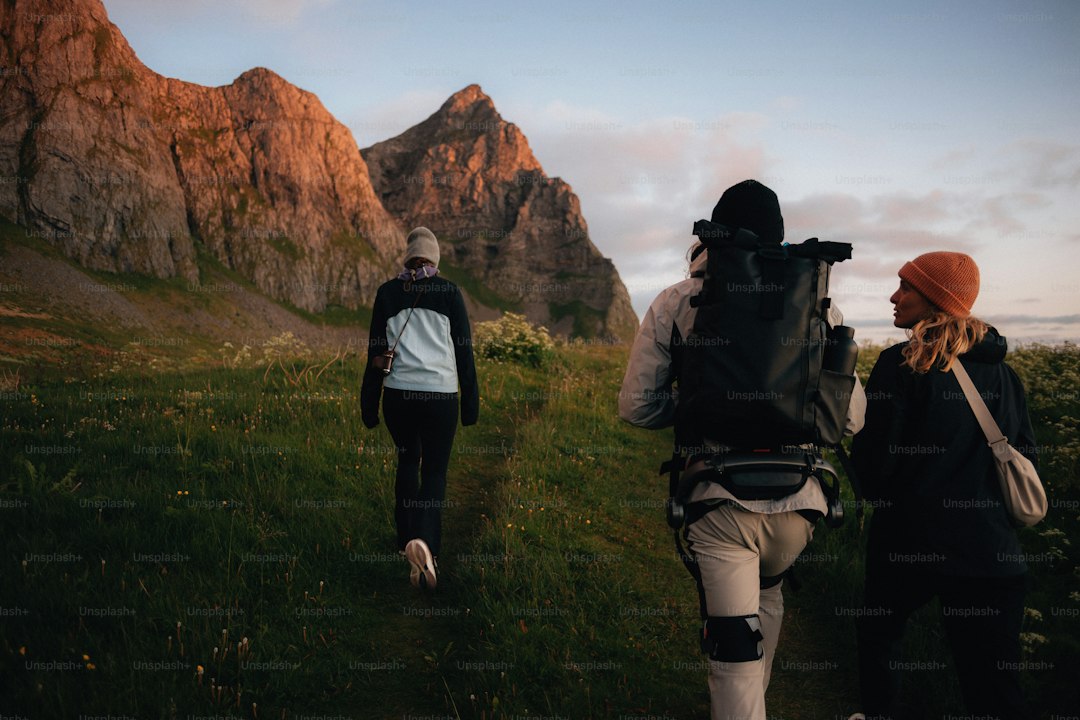 Three hikers explore a mountainous trail at dusk.