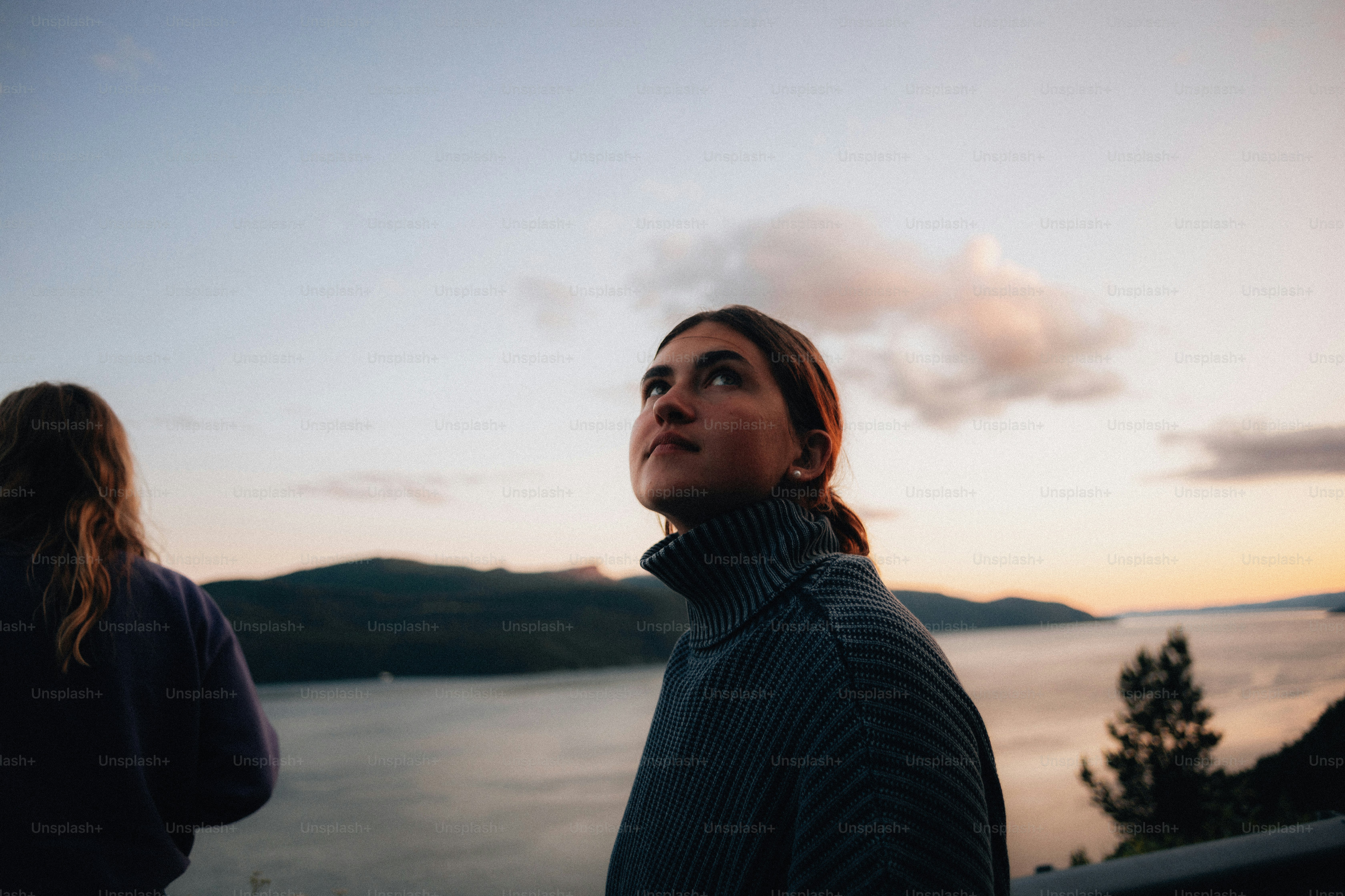 Frau, die in den Sonnenuntergangshimmel blickt.