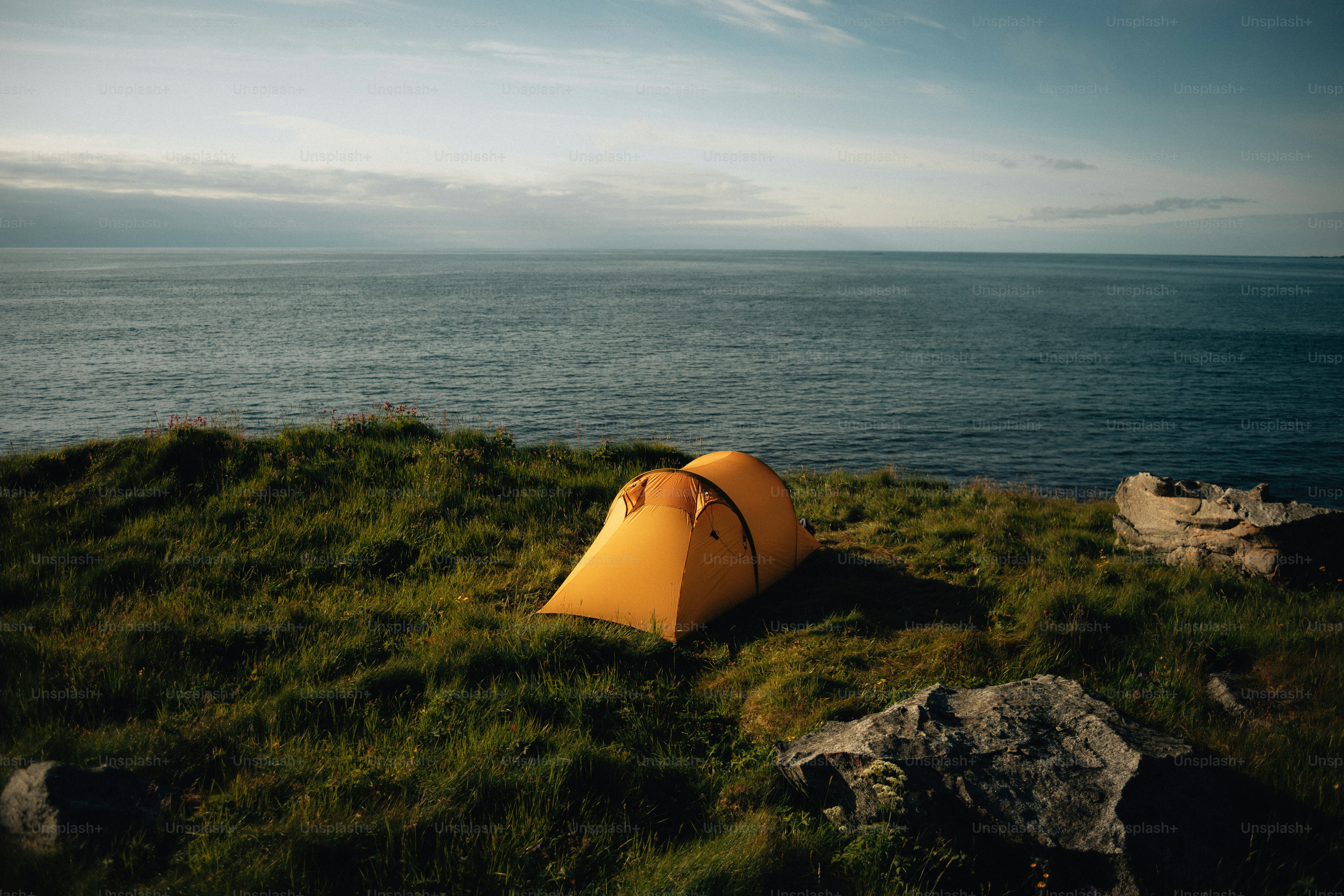 Ein Zelt steht auf einem Hügel mit Blick auf das Meer.
