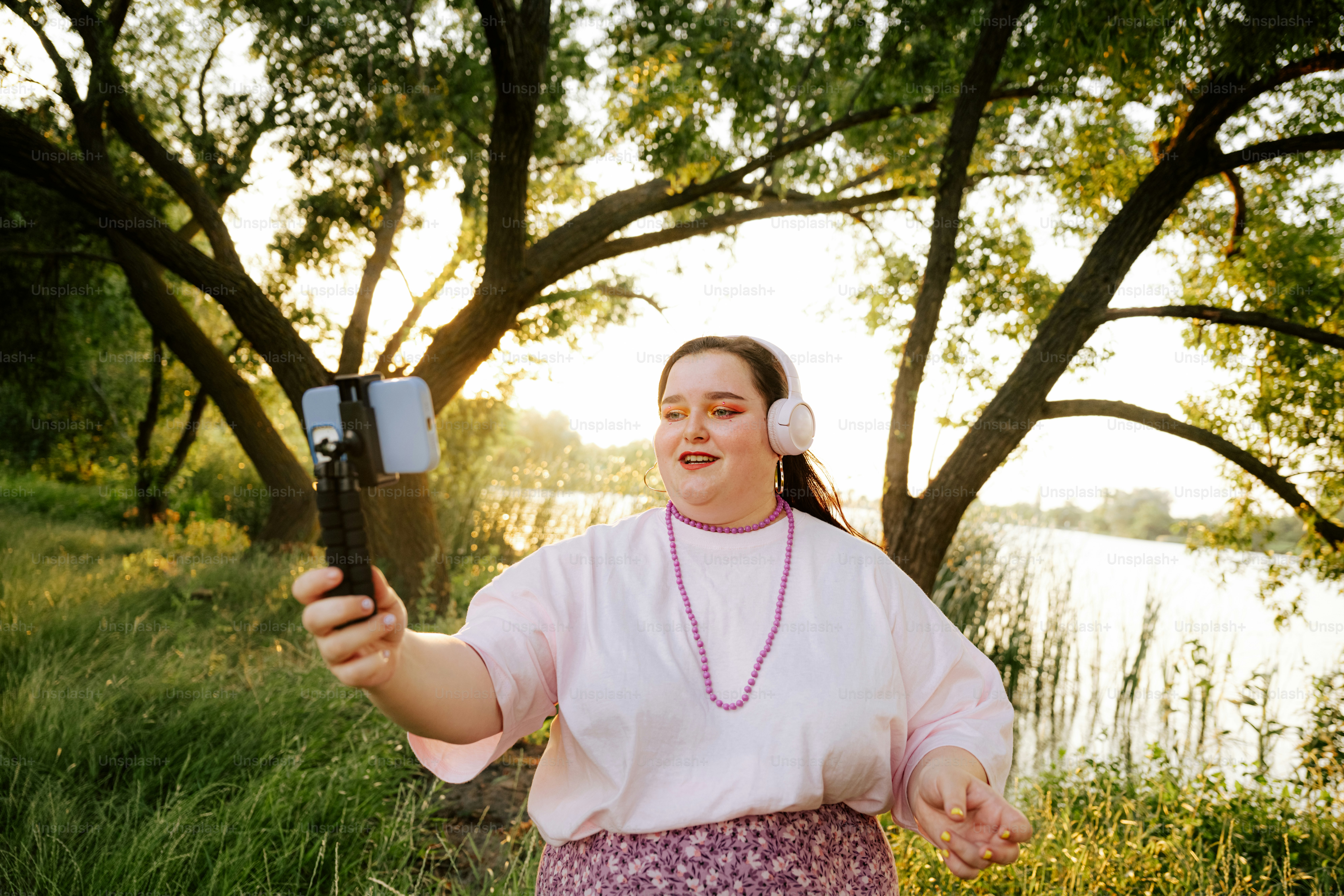 A woman records herself outdoors with a phone.