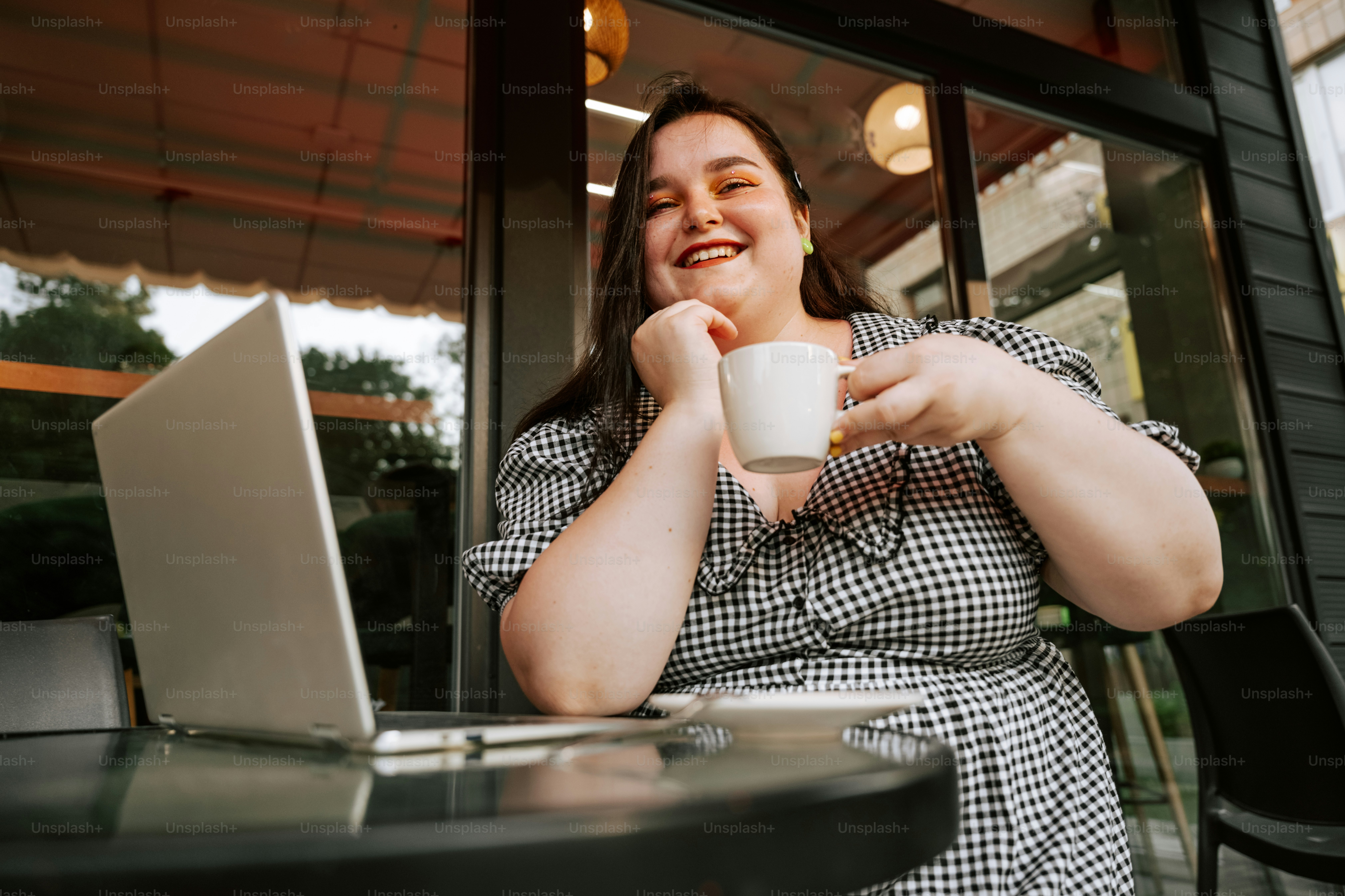 Woman smiles while drinking coffee and working.