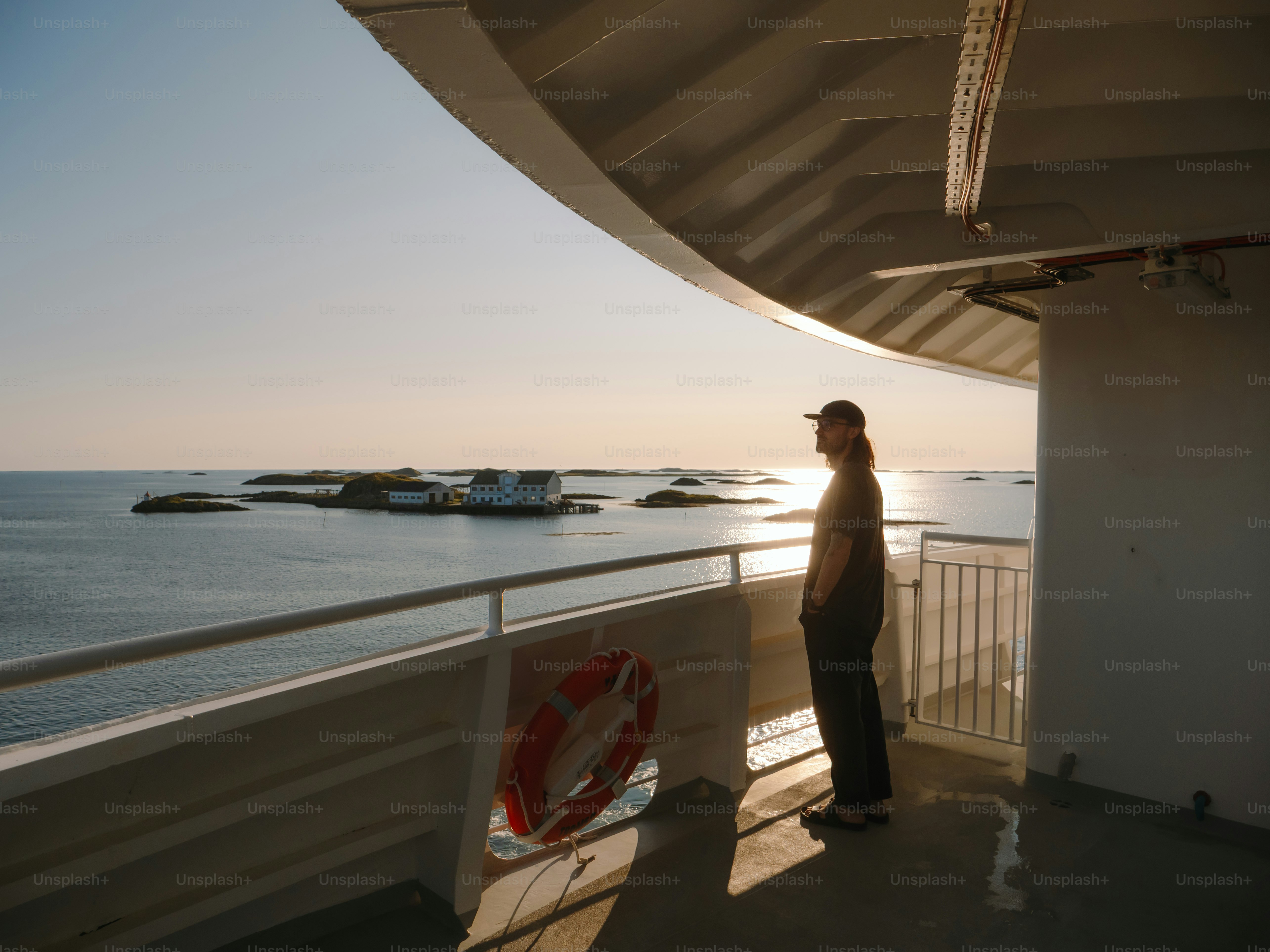 A man stands on a boat, watching the ocean.