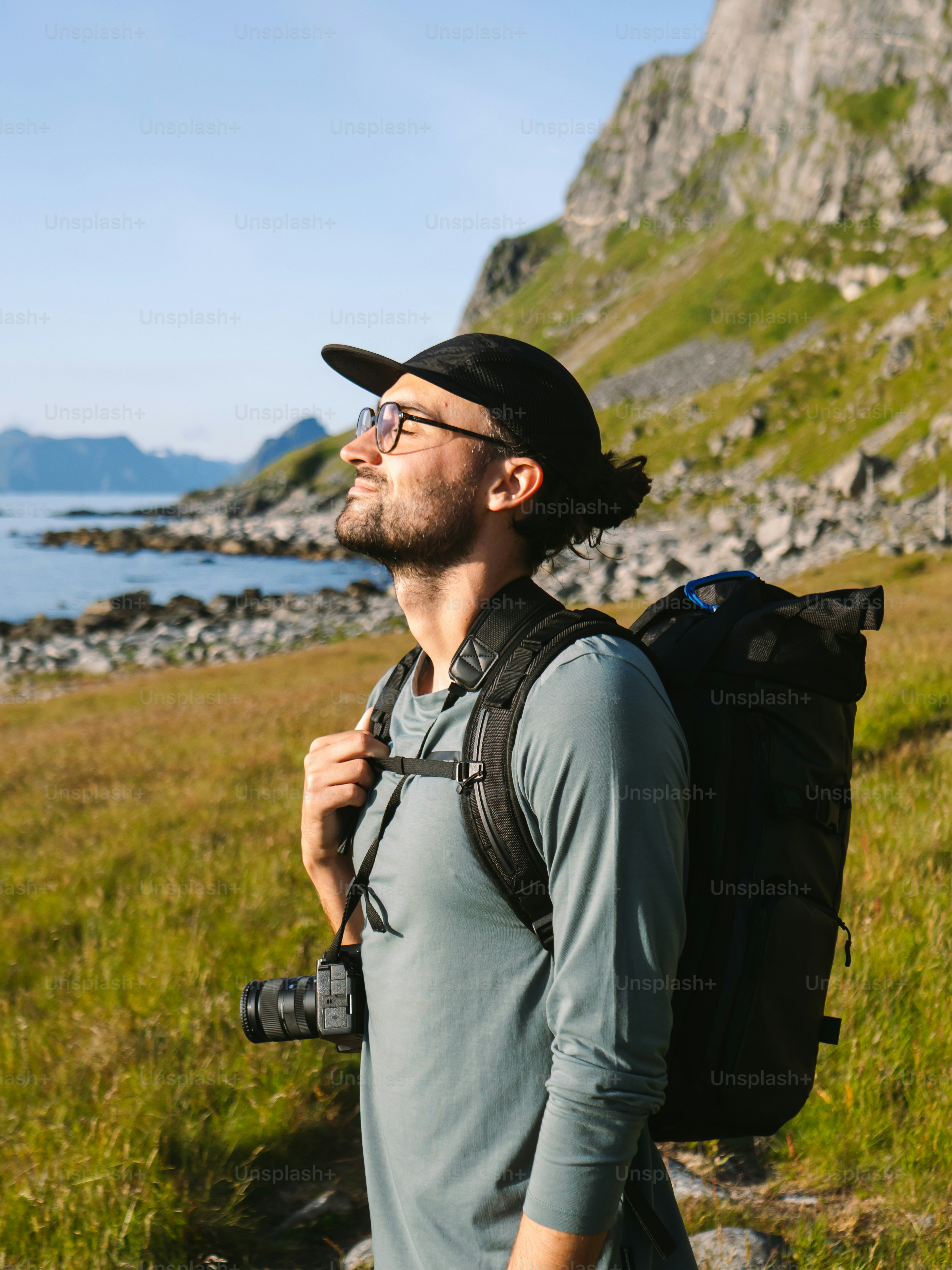 A hiker smiles while looking up at the mountains.