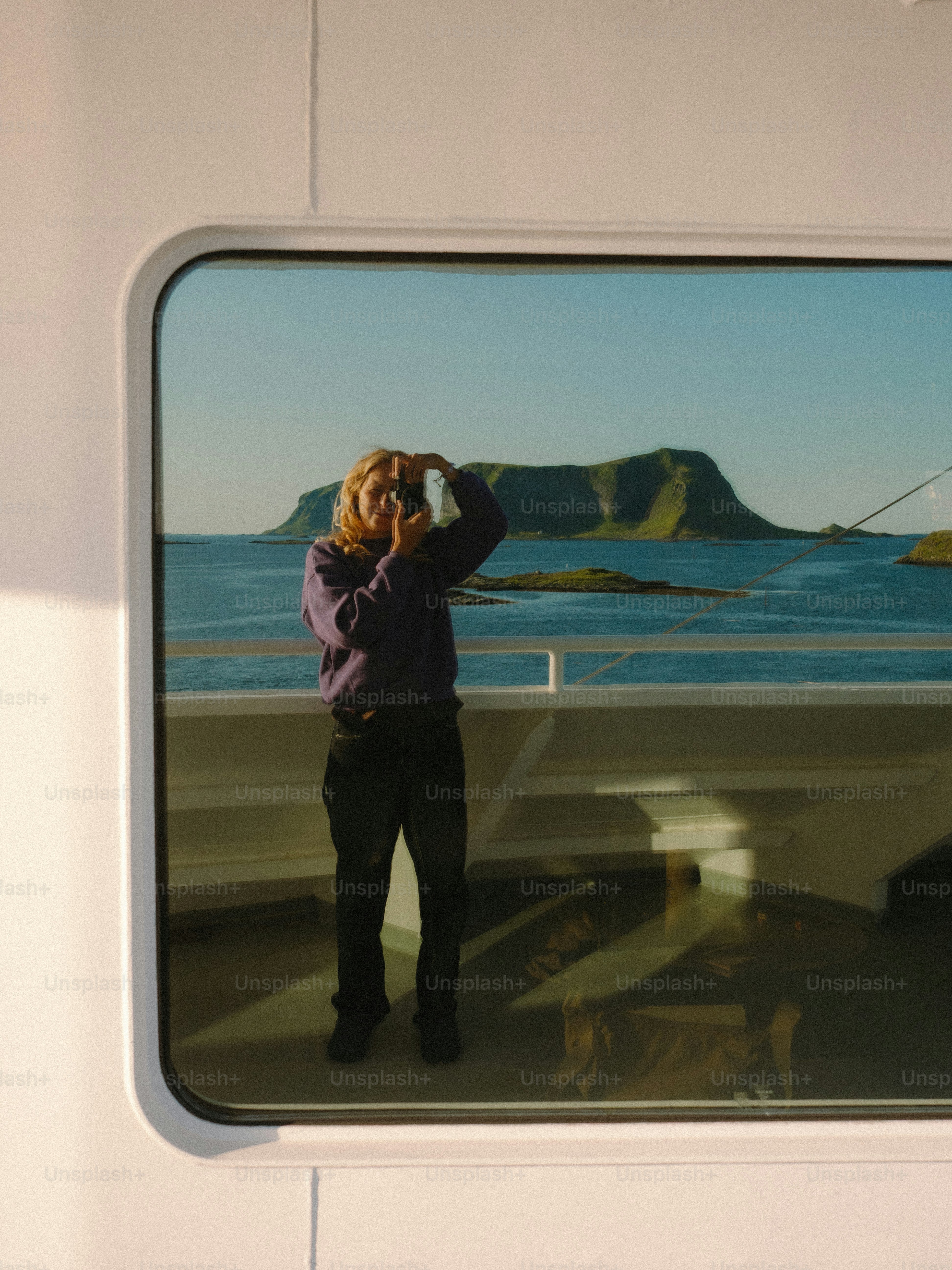 A person photographs scenery from a ship.