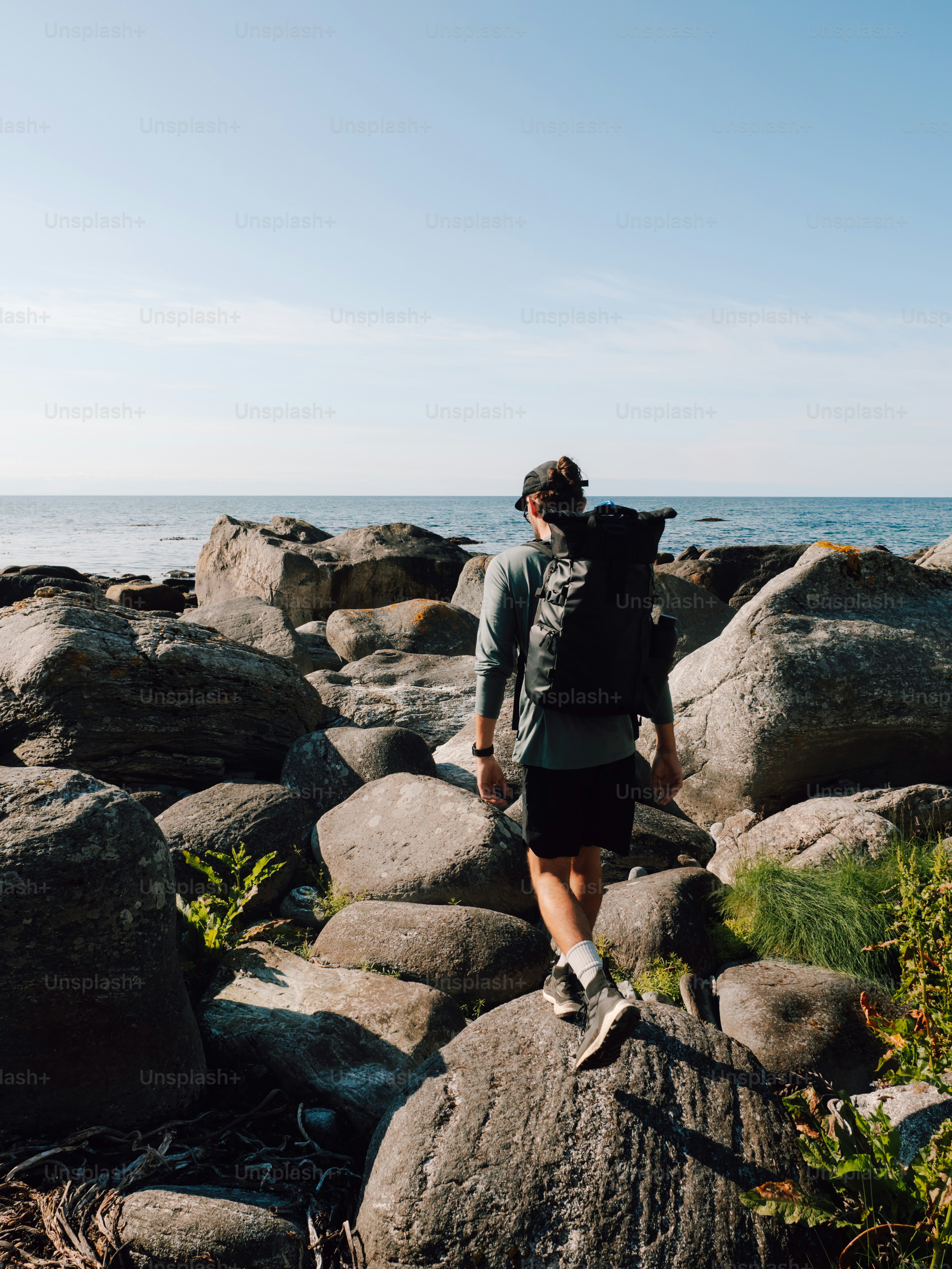 Hiker walks on rocks near the ocean.