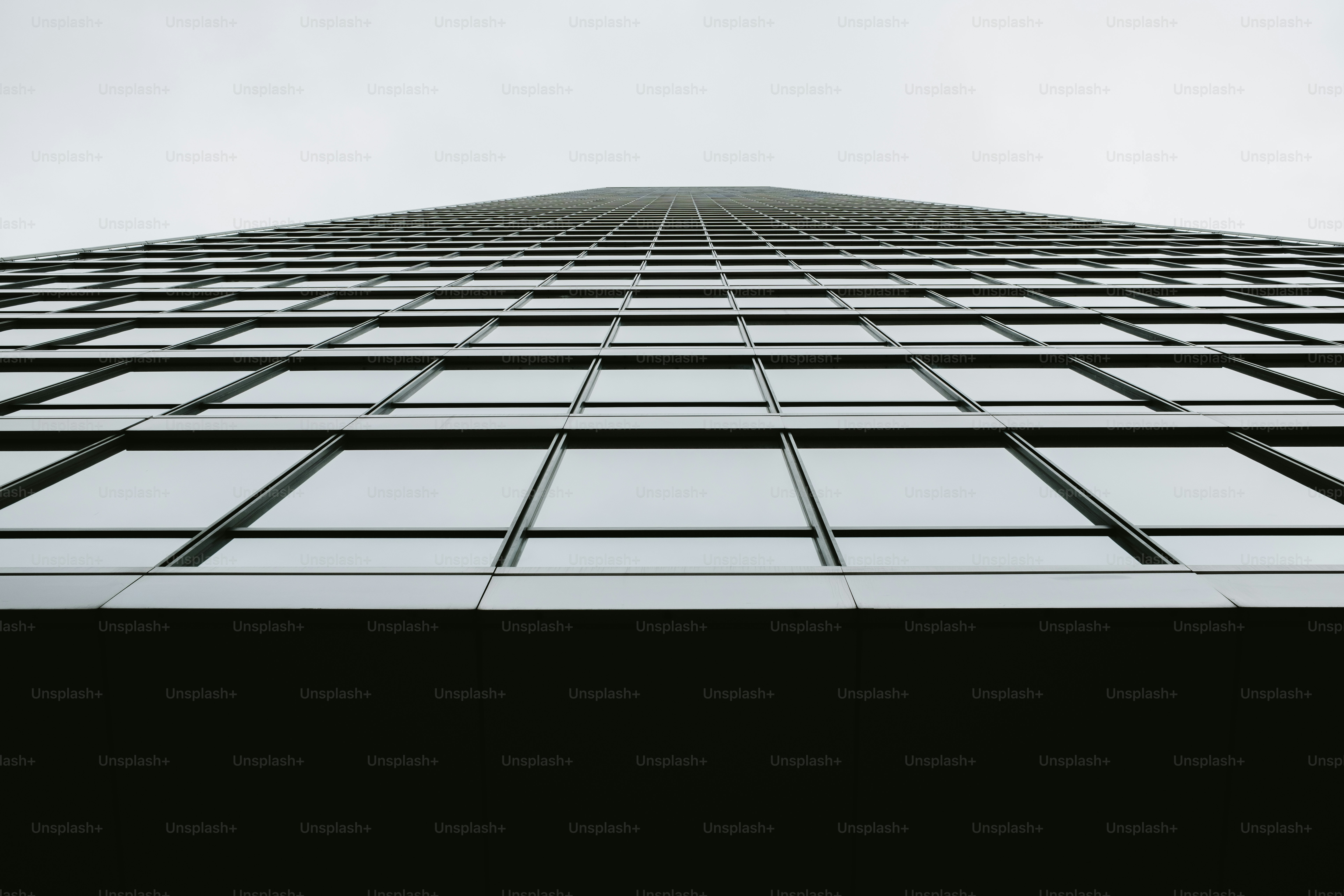 A low angle view of a glass skyscraper facade with a grid pattern