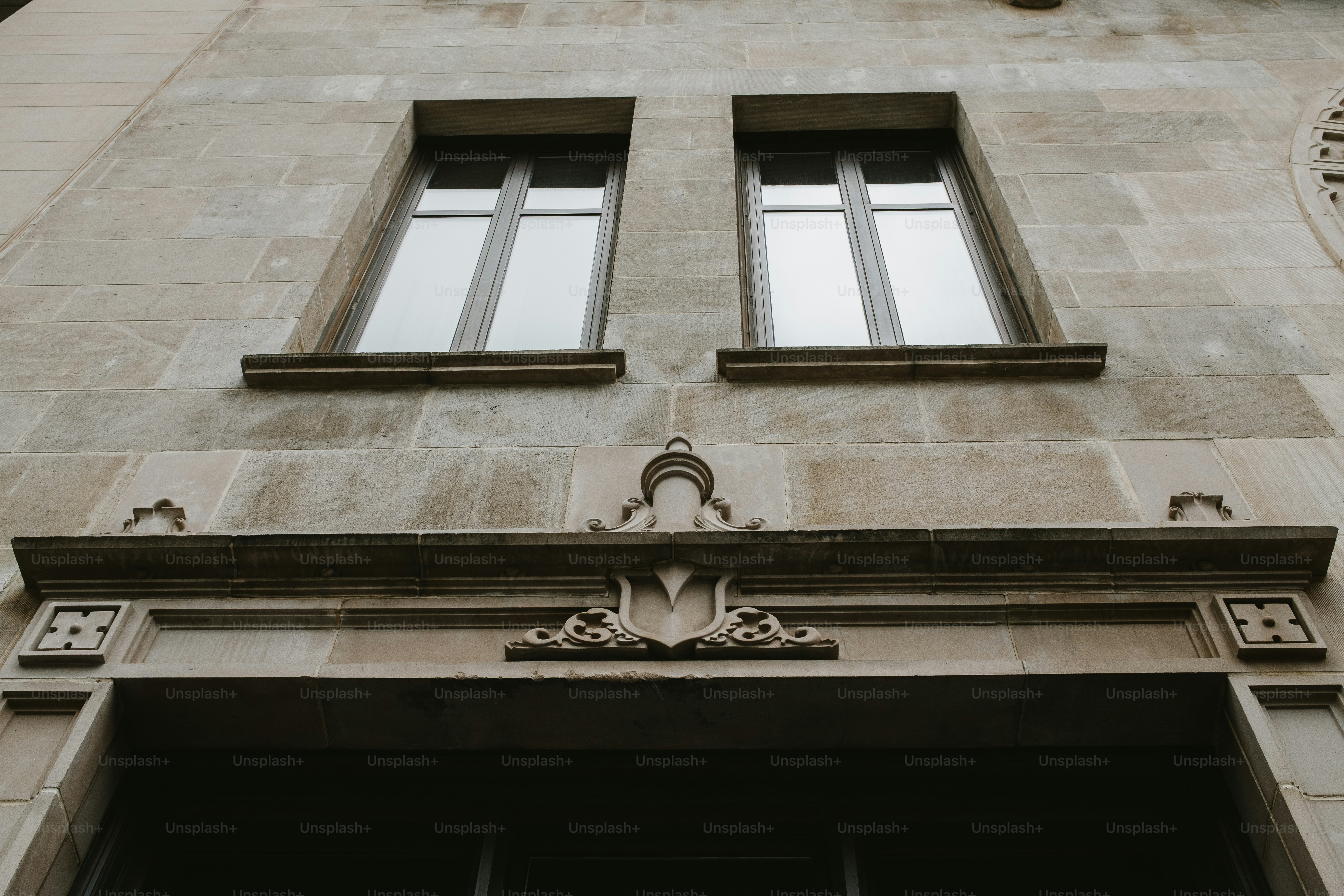 Zwei Fenster befinden sich über einem verzierten Steineingang.