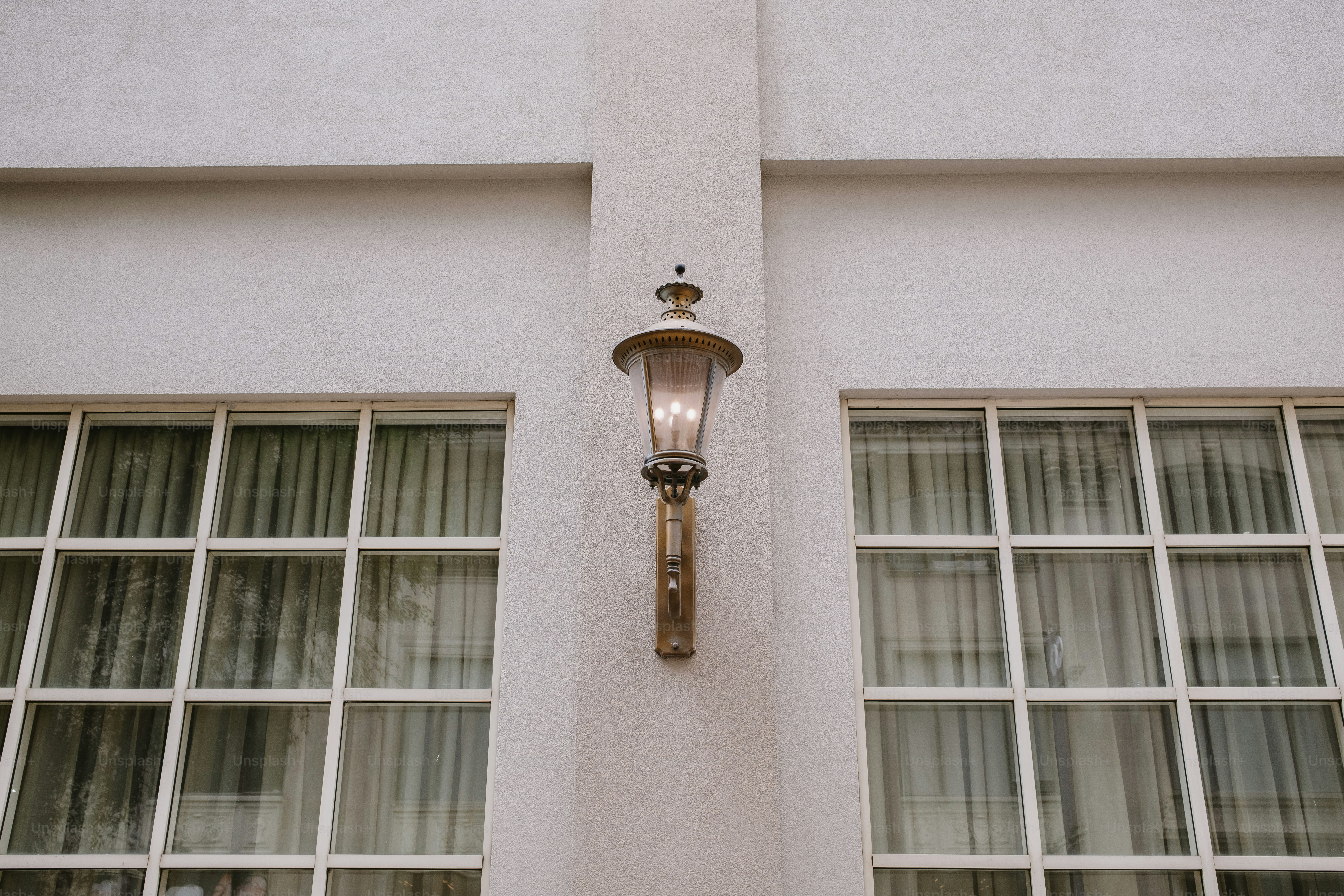 A wall-mounted lamp is beside two windows. photo – Architecture Image ...