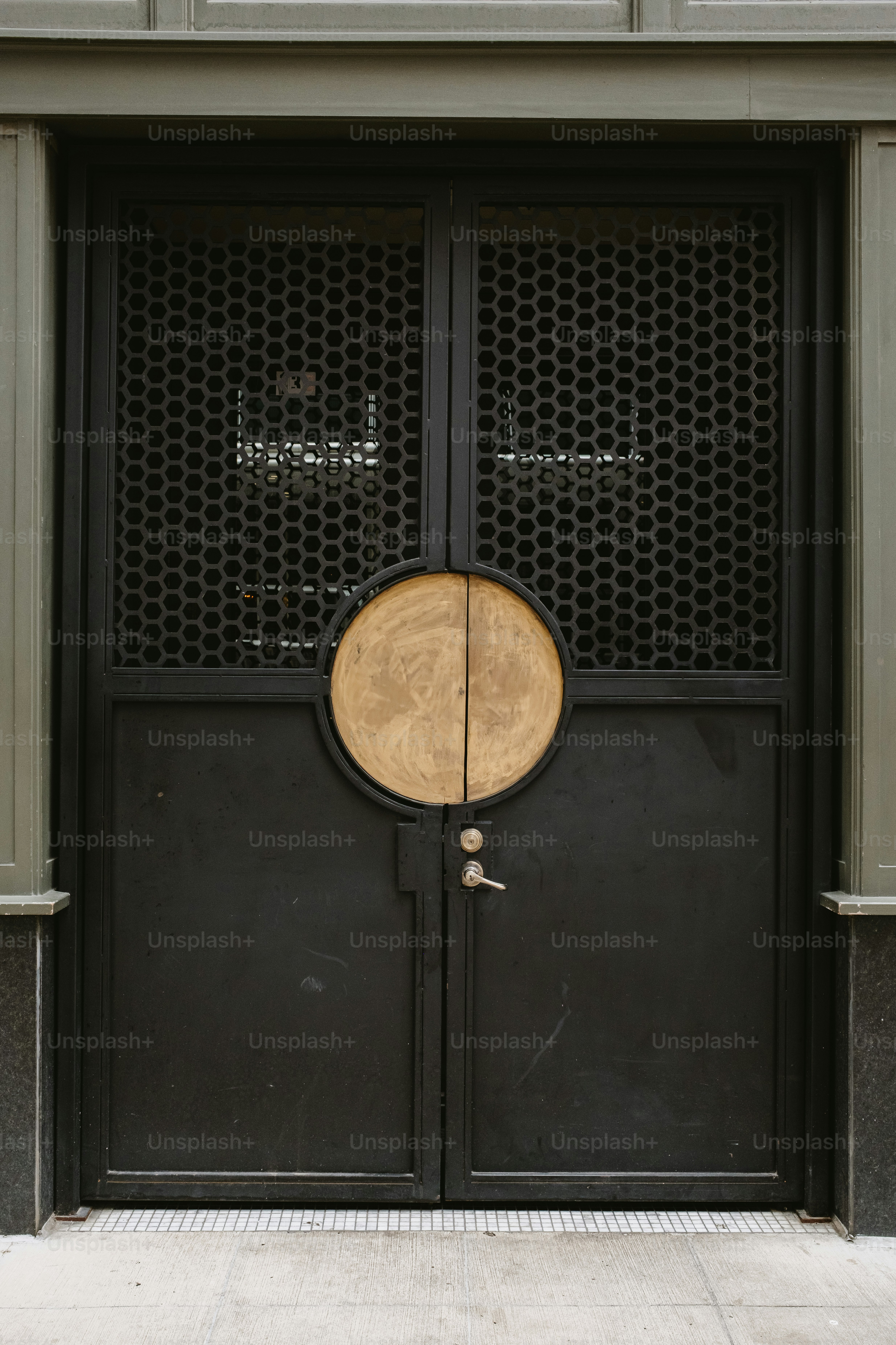 Black, metal door with circular accent and grillwork.