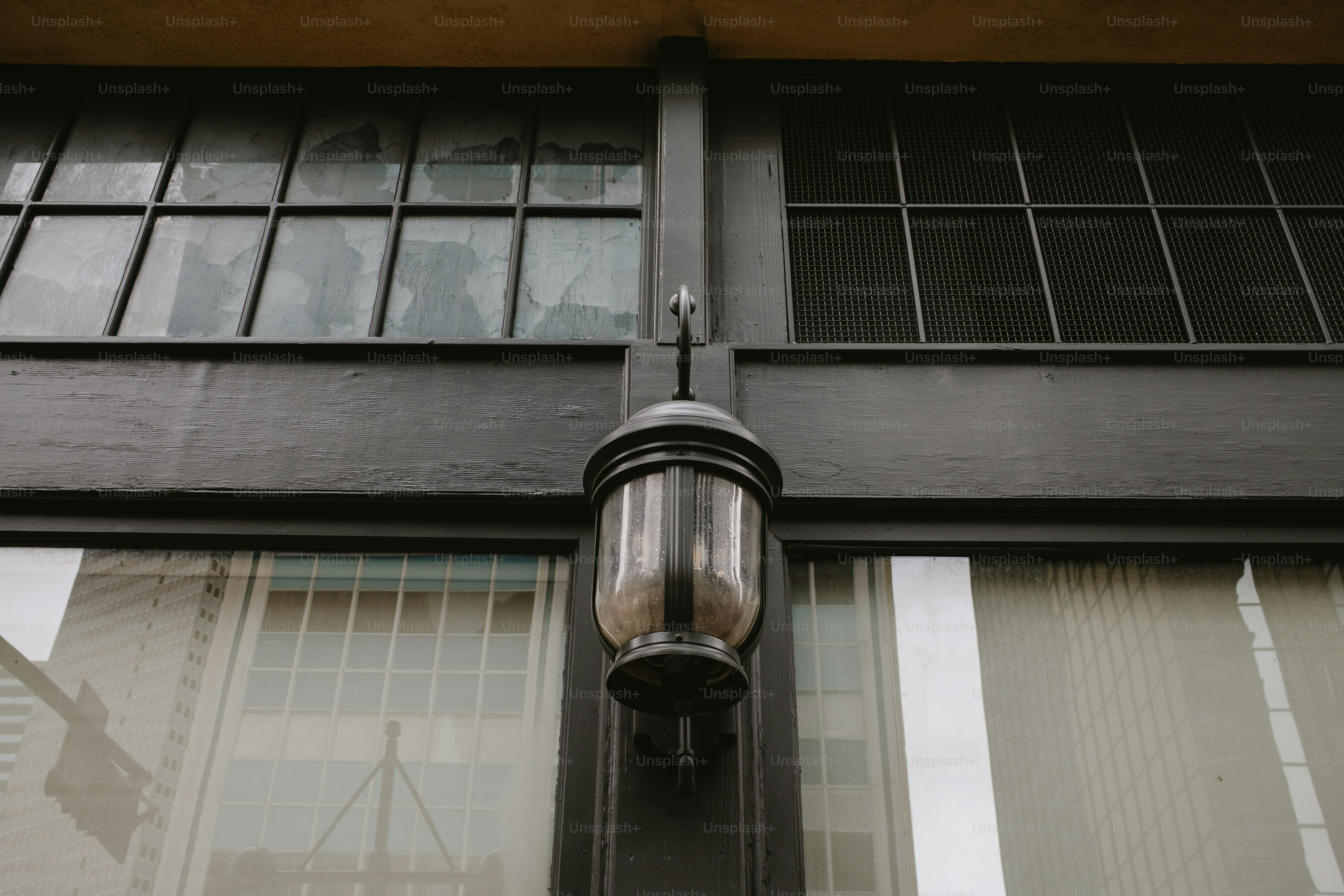 Eine alte Lampe hängt zwischen den Fenstern eines Gebäudes.