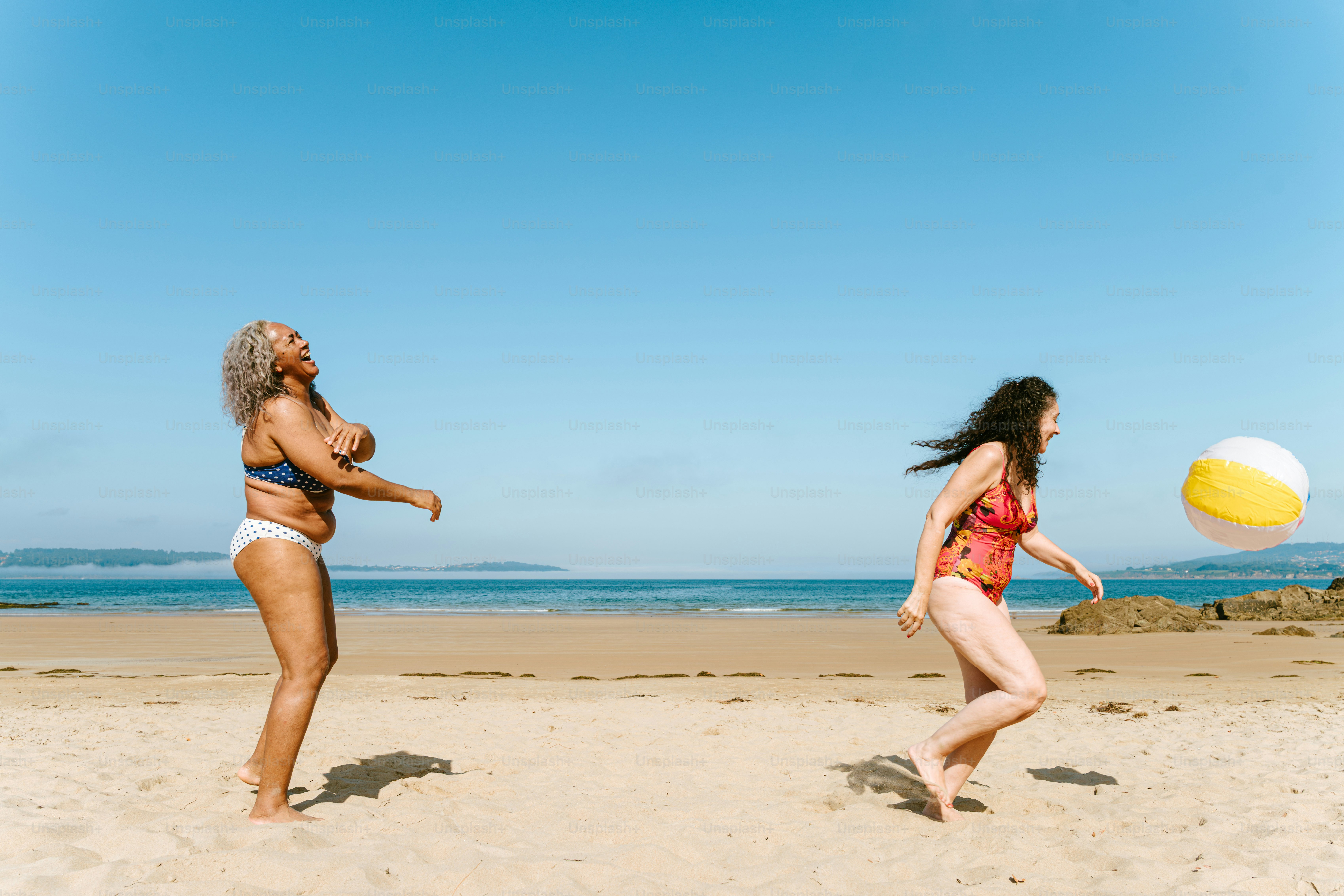 Women are playing volleyball on a sunny beach.
