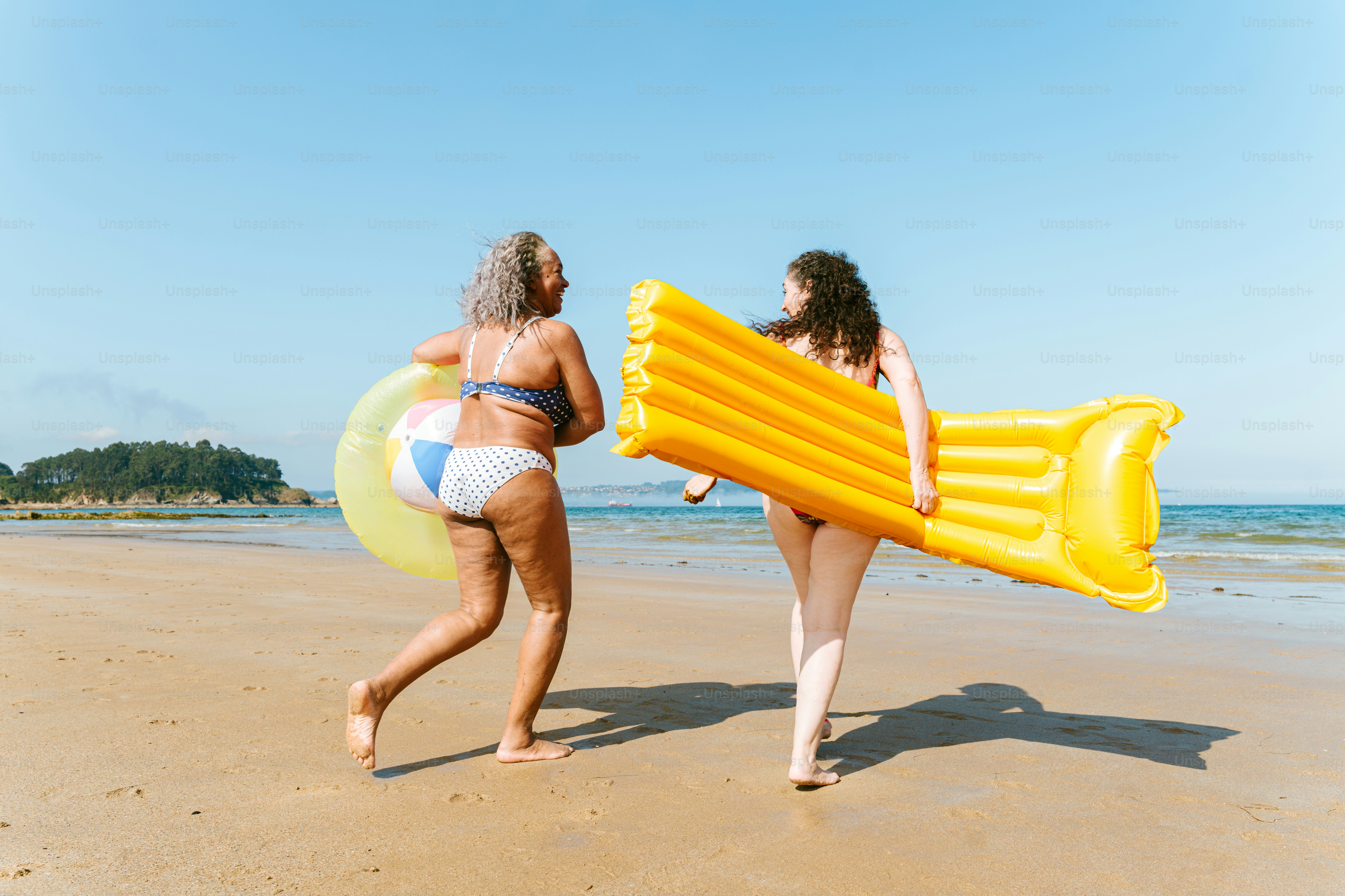 Two women enjoy the beach with inflatables.