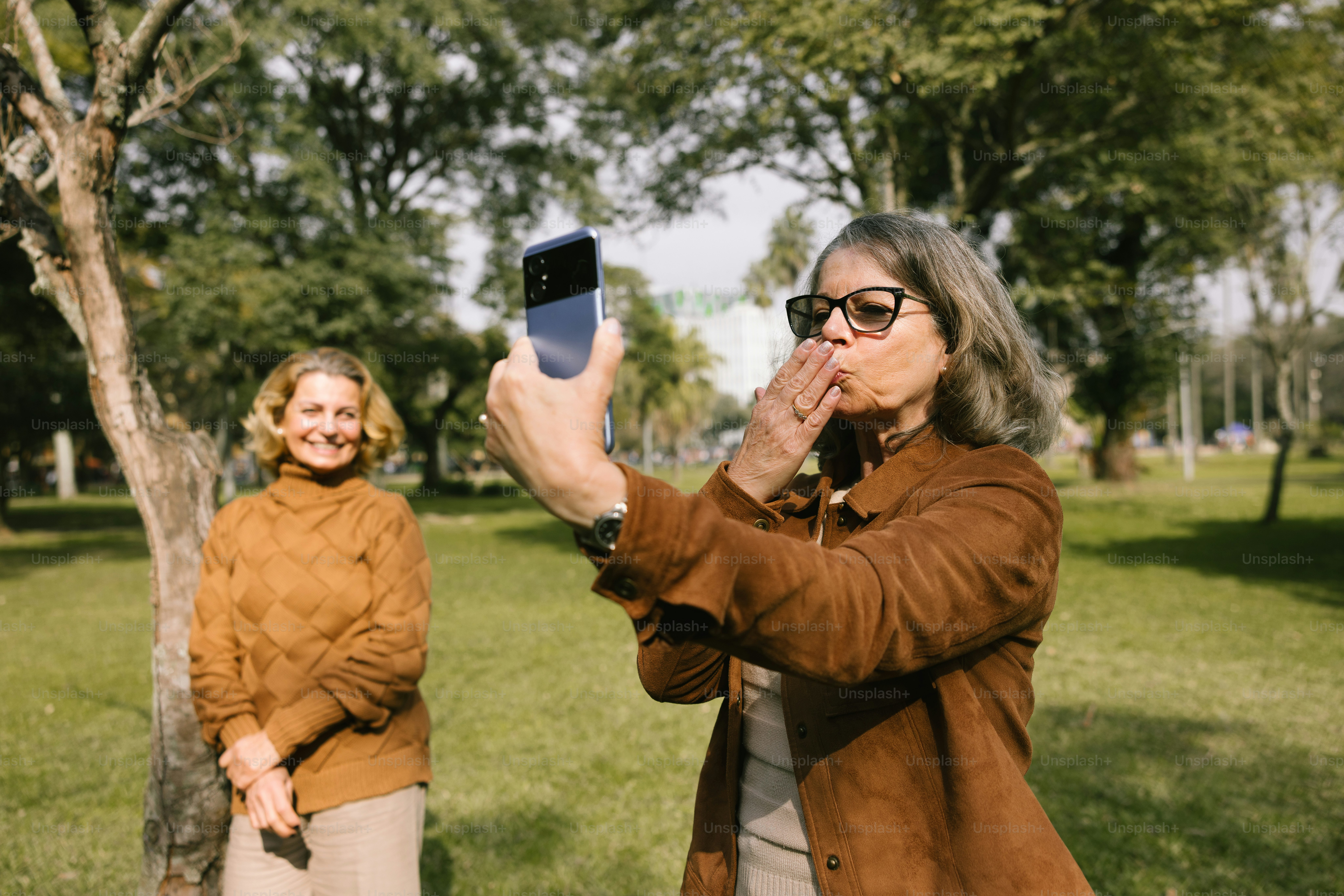 Two women take a selfie in a park.