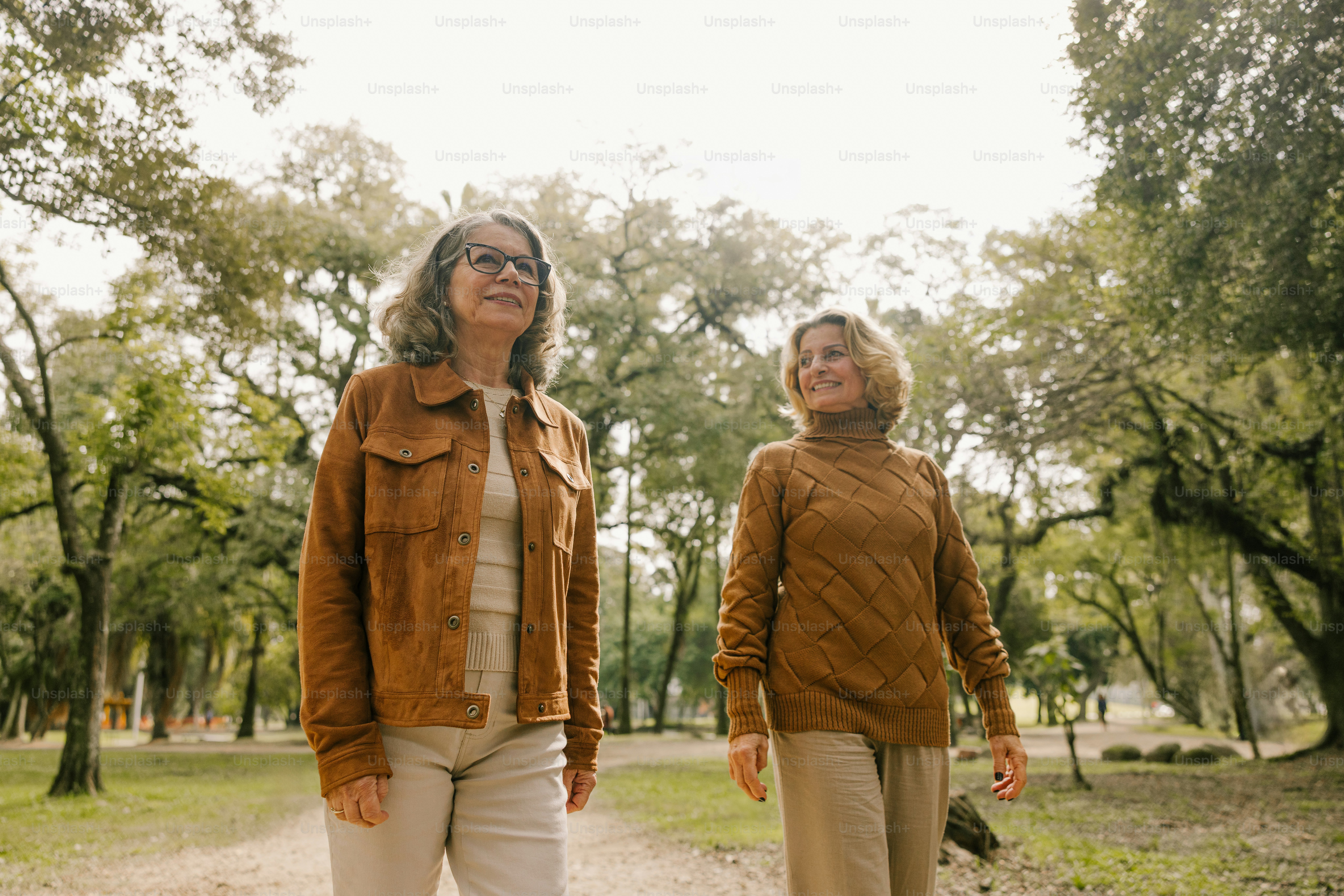 Two women stroll and smile in a park.