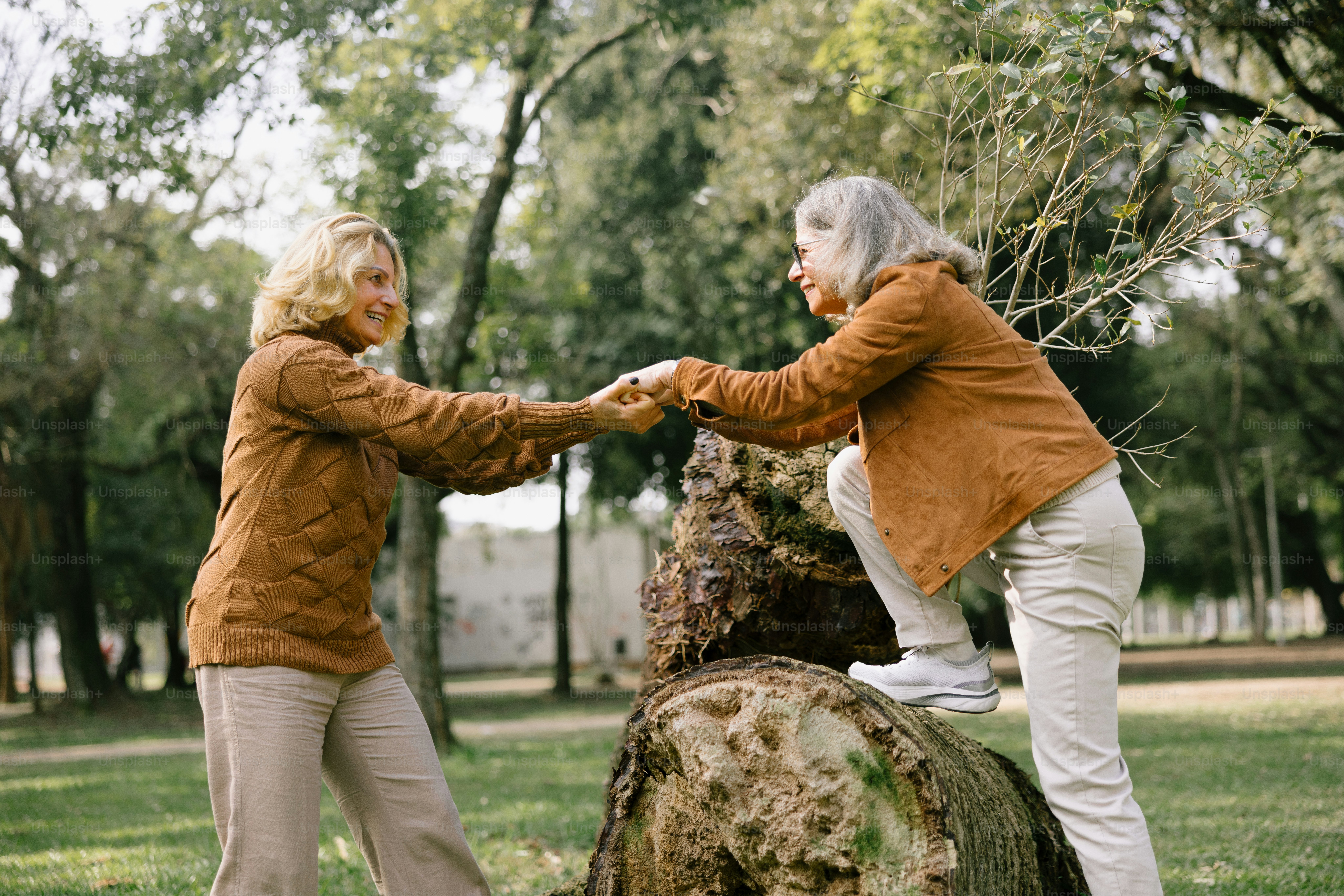 Two women help each other in a park.