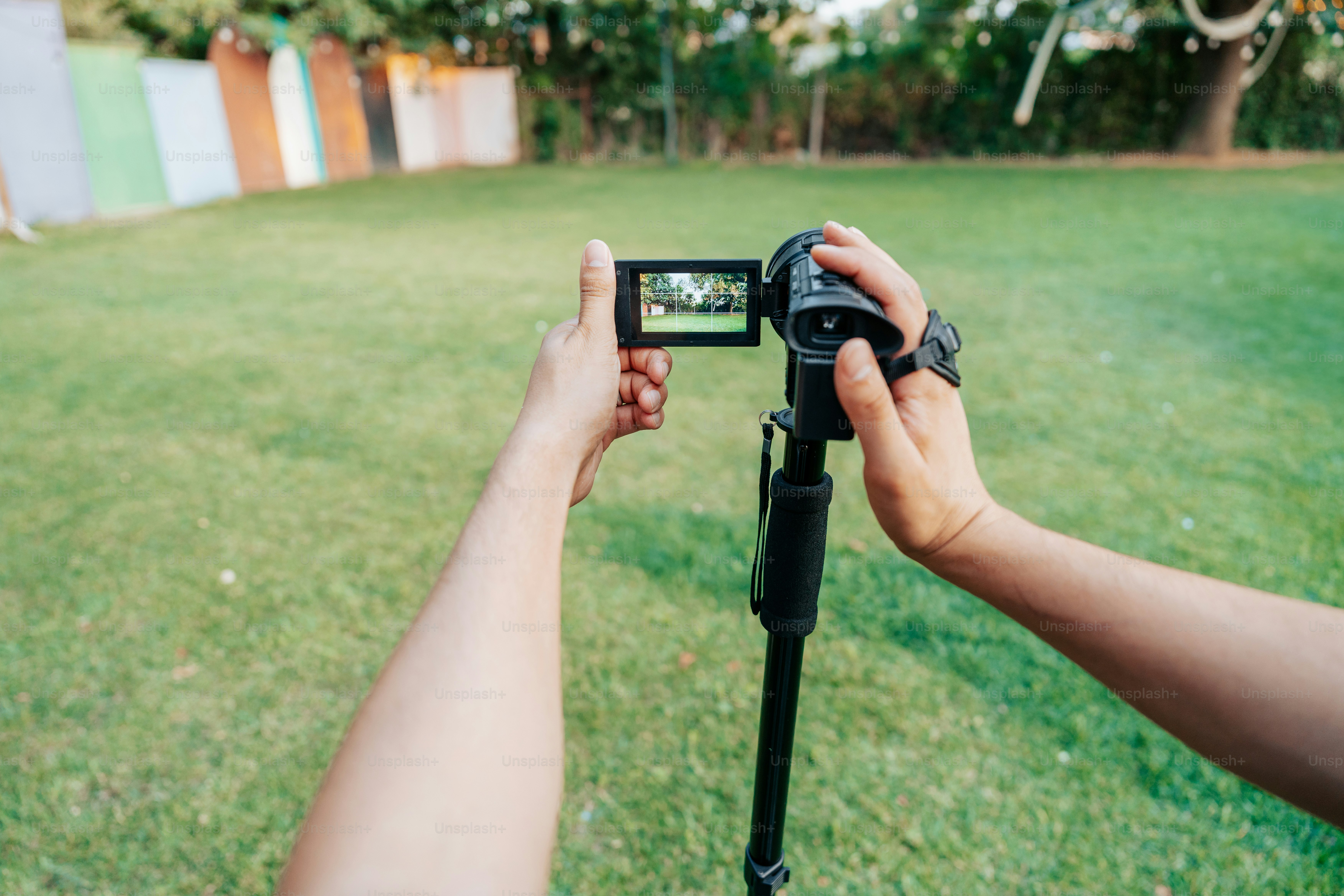 Filming with a camcorder on a tripod outdoors.