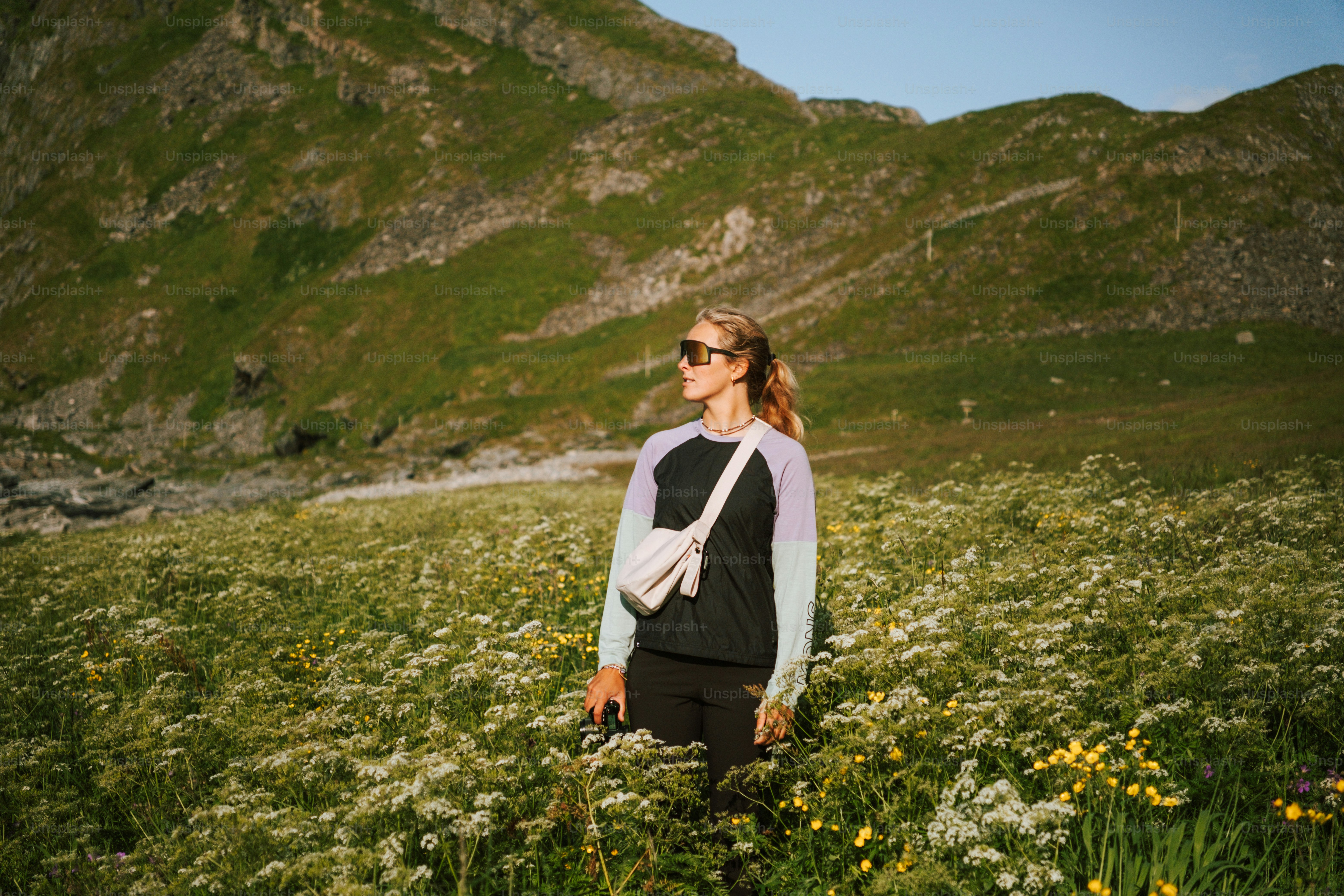 Die Frau steht auf dem Feld, die Berge hinter sich.