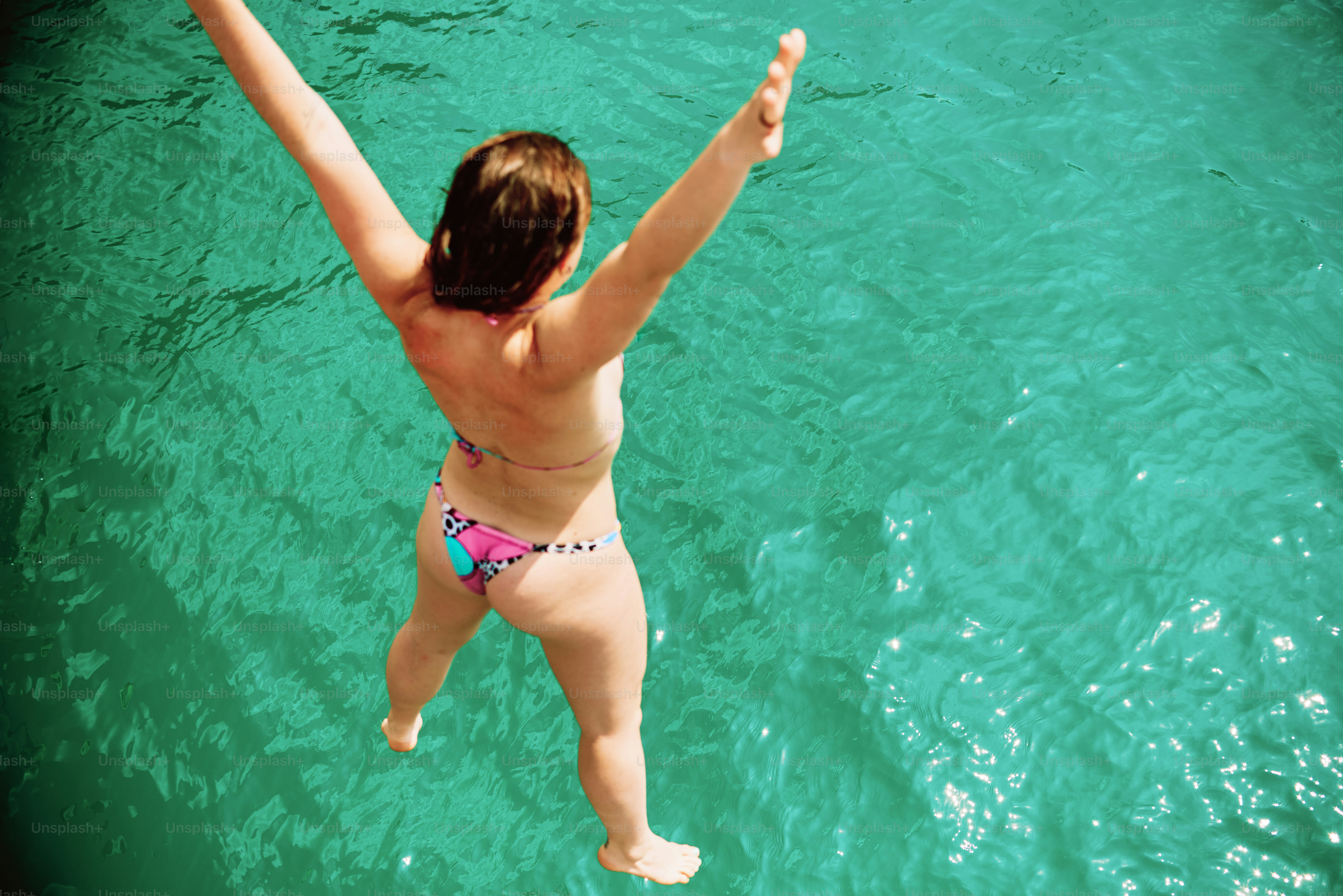 Eine Frau springt ins türkisfarbene Wasser.