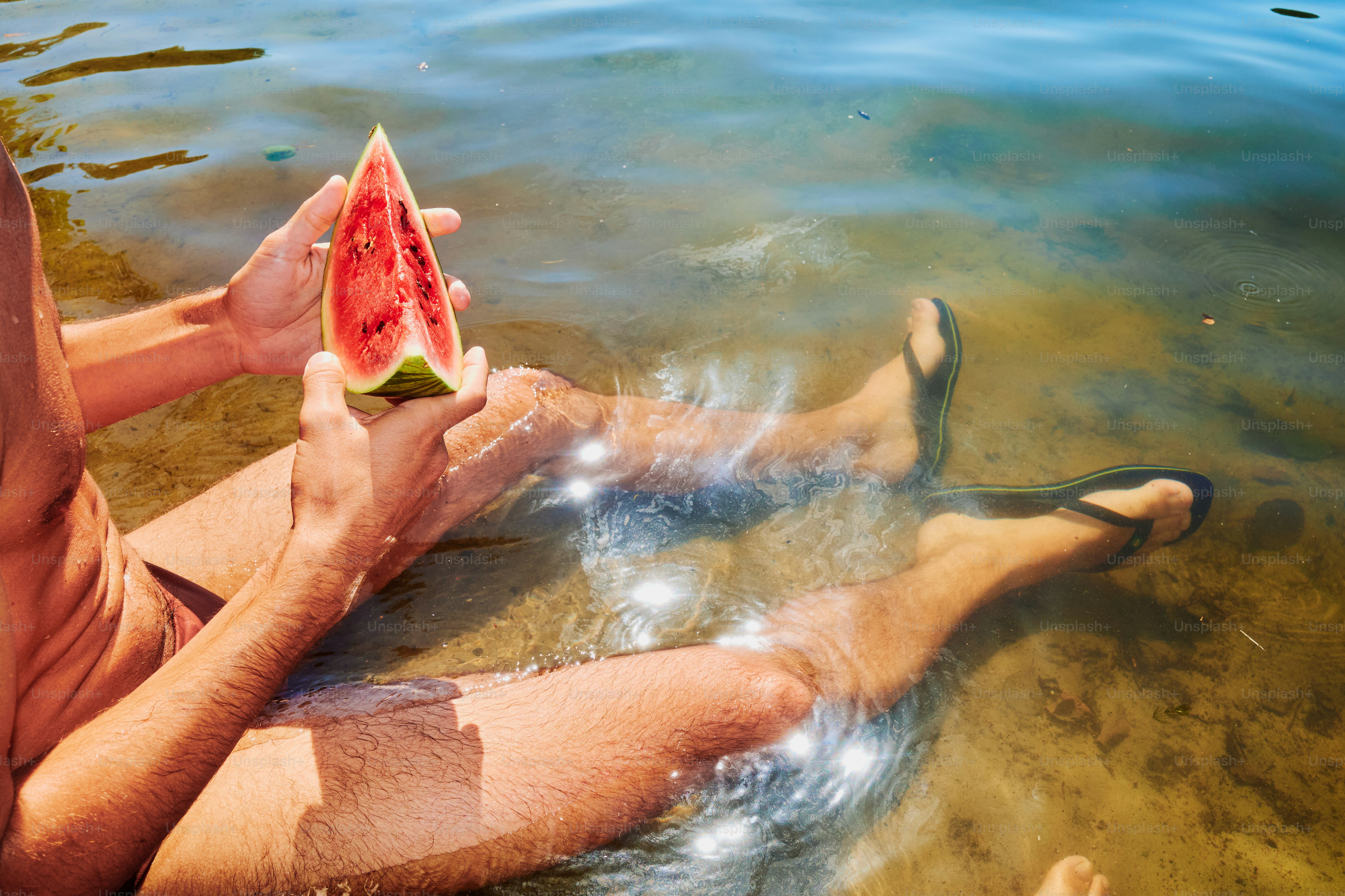 Mann genießt Wassermelone im Wasser.