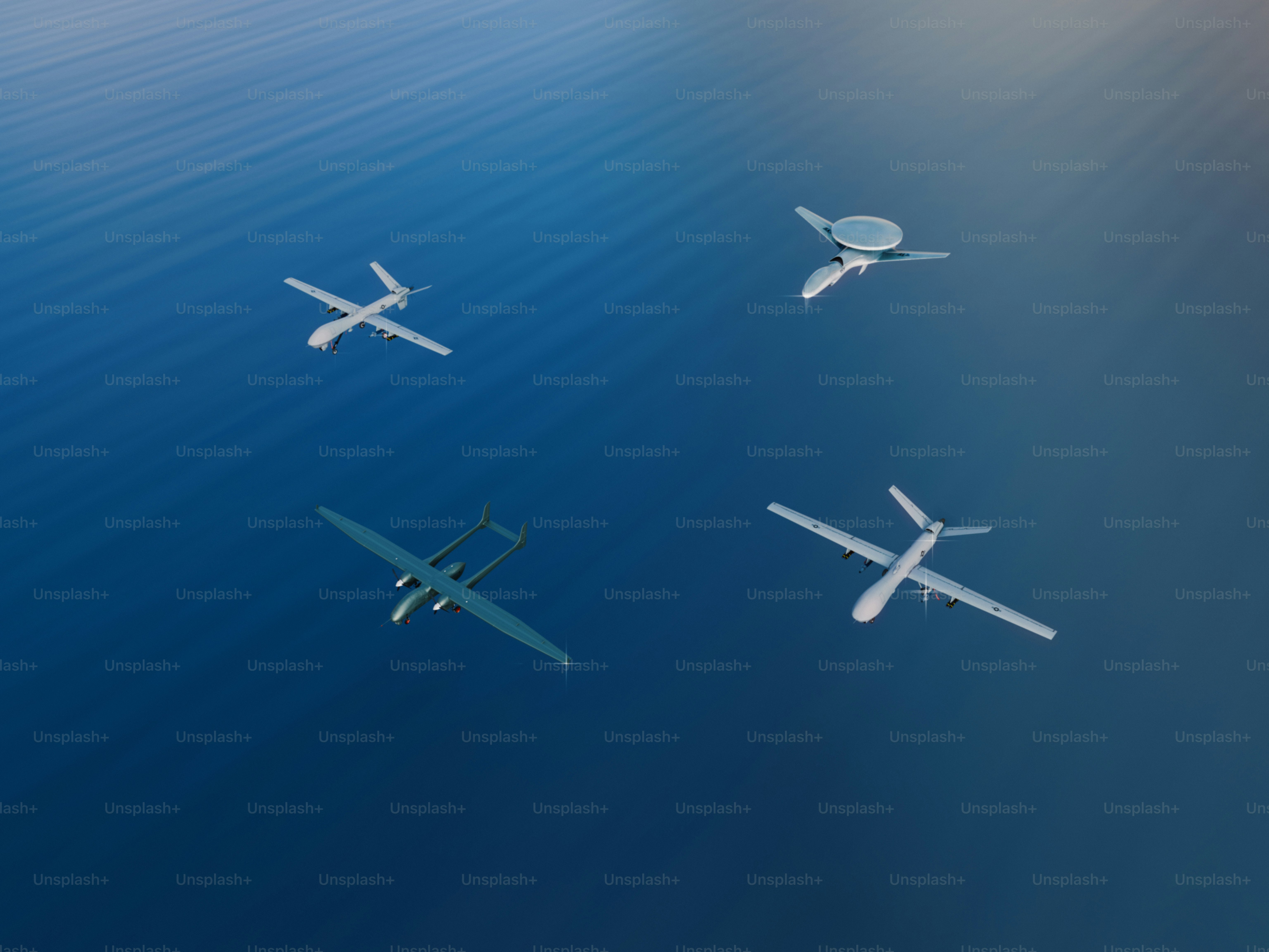 Four drones fly in the sky above water.
