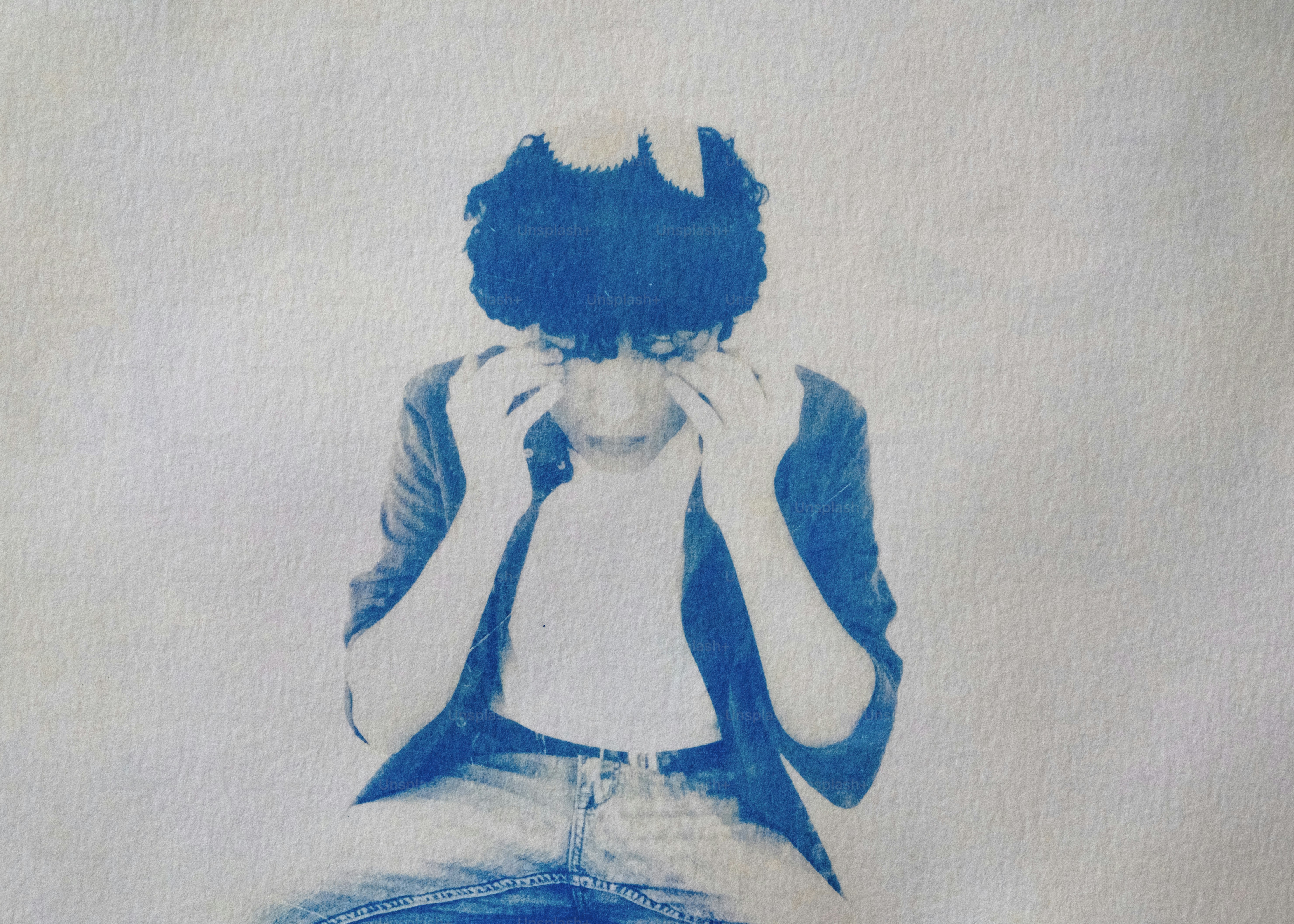 A person covers their face in a blue hued image.