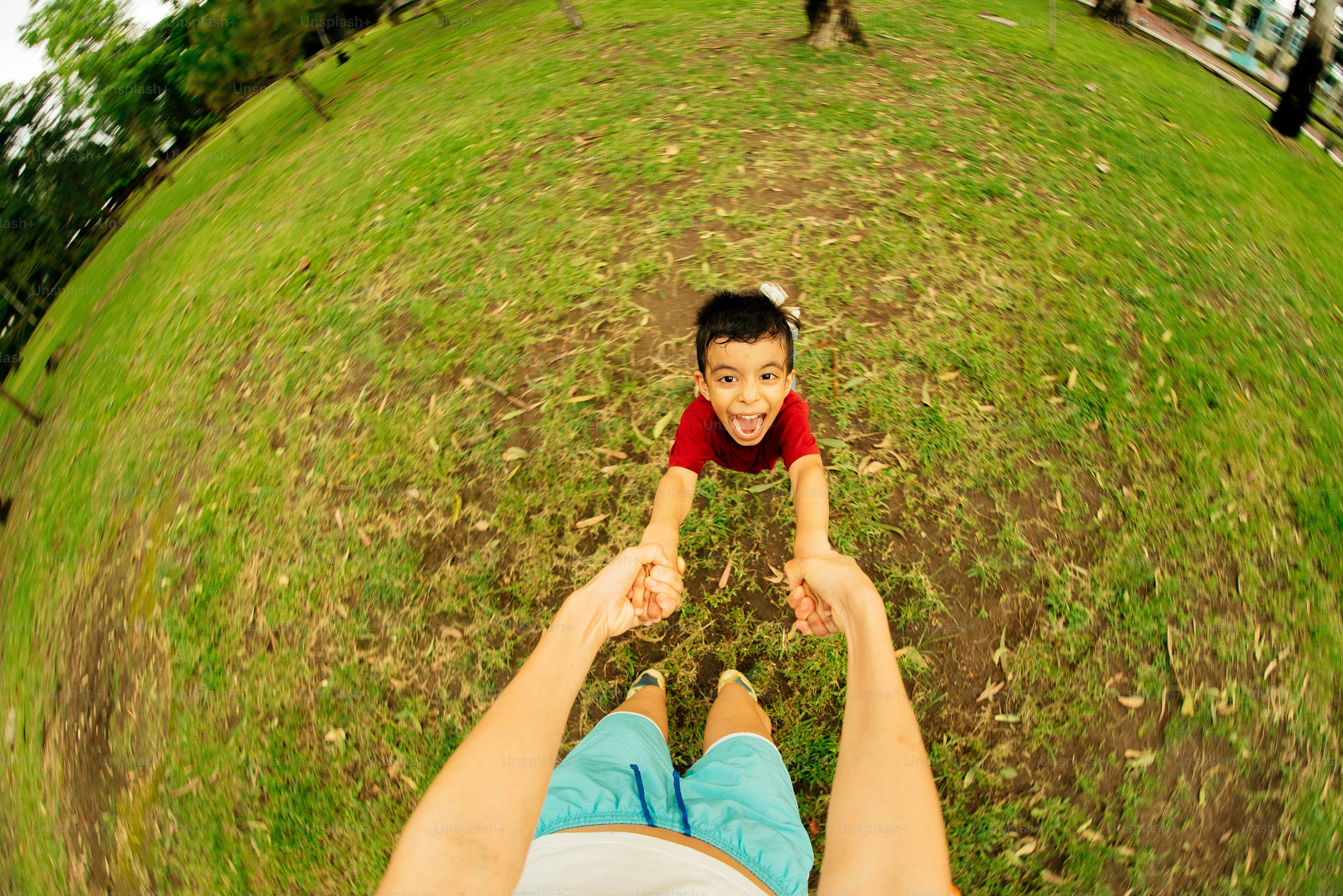 Someone is swinging a happy child in the park.