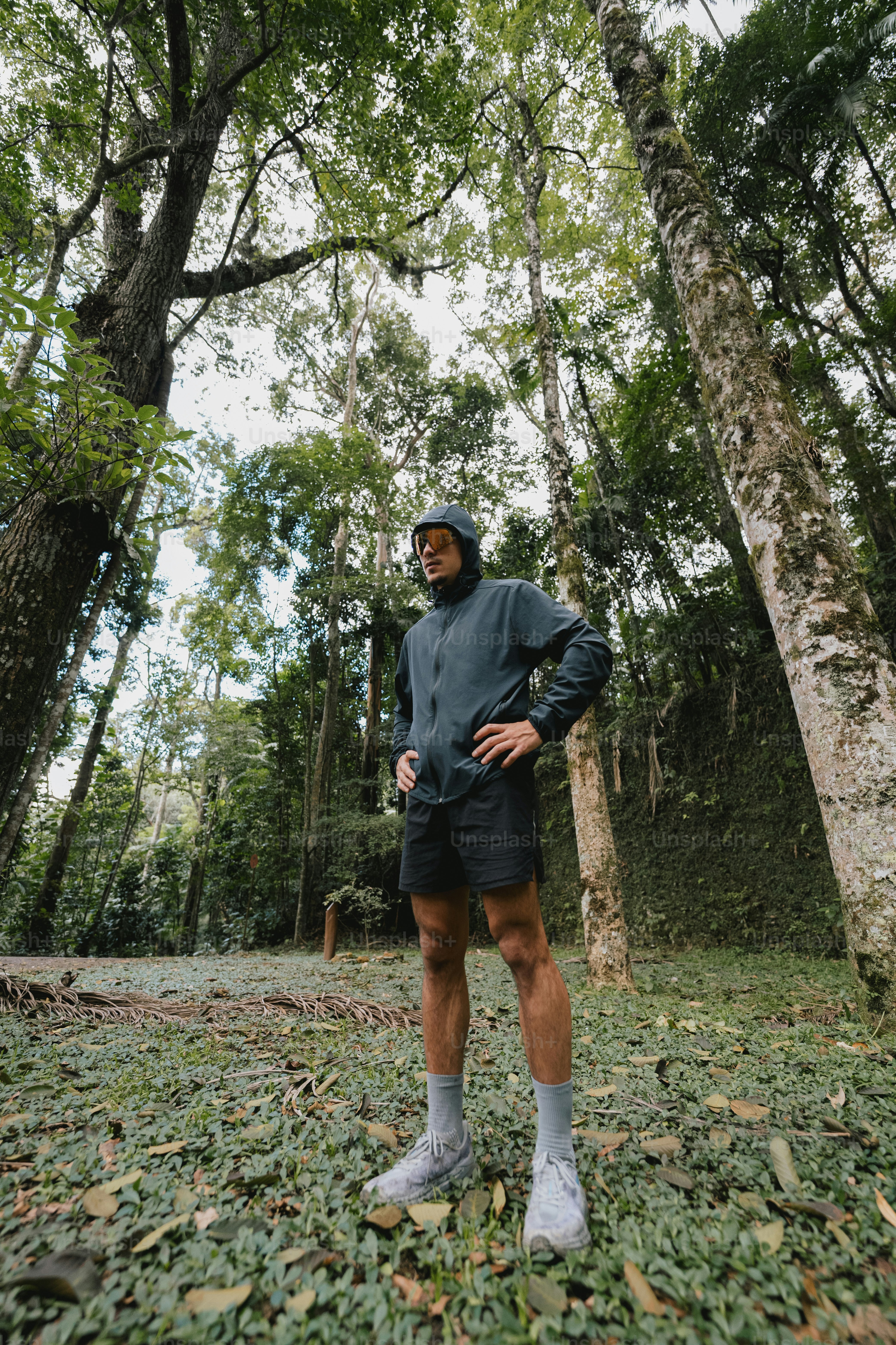 Seorang pria berpakaian aktif berdiri di hutan.