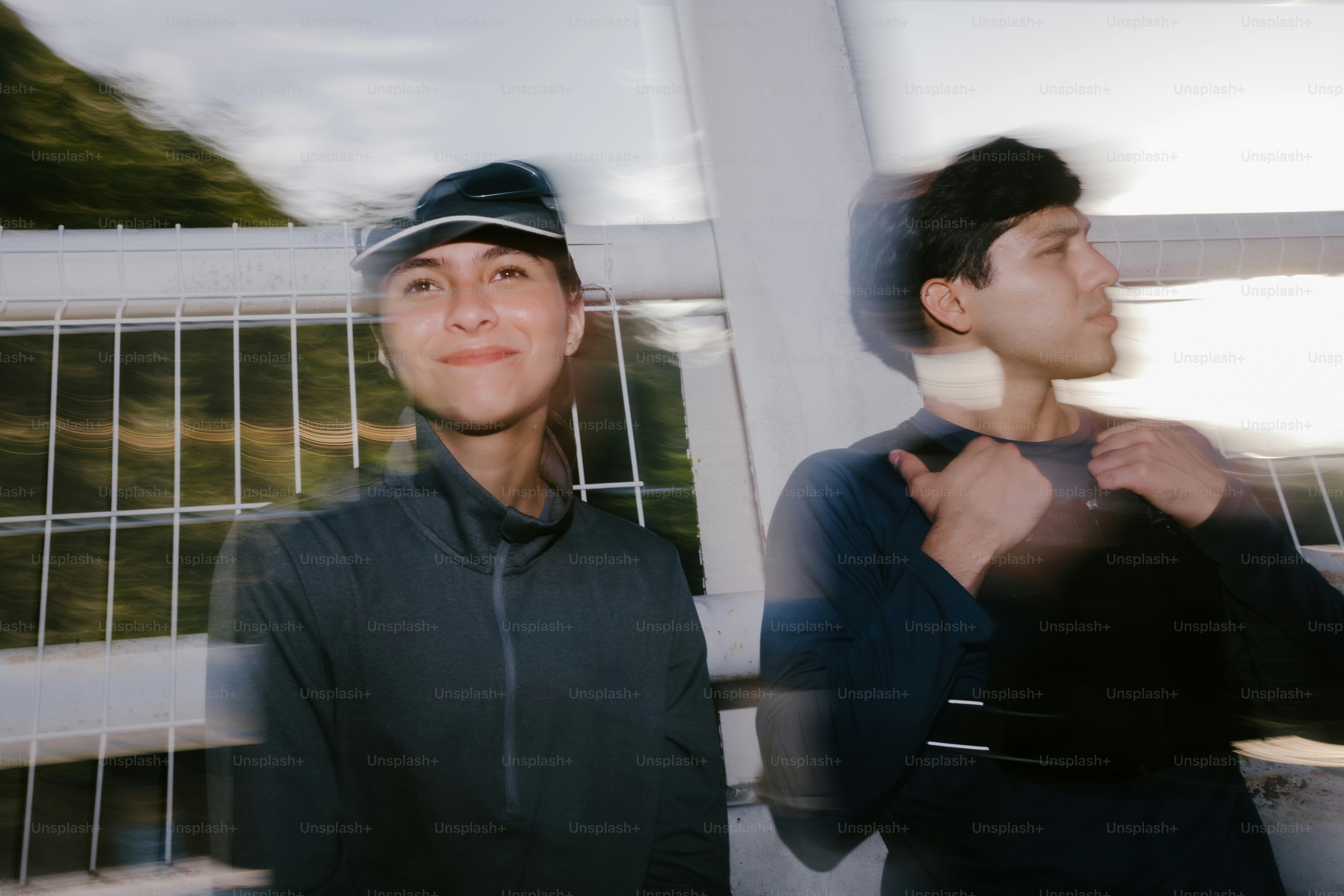 Two people pose outdoors on a bridge.