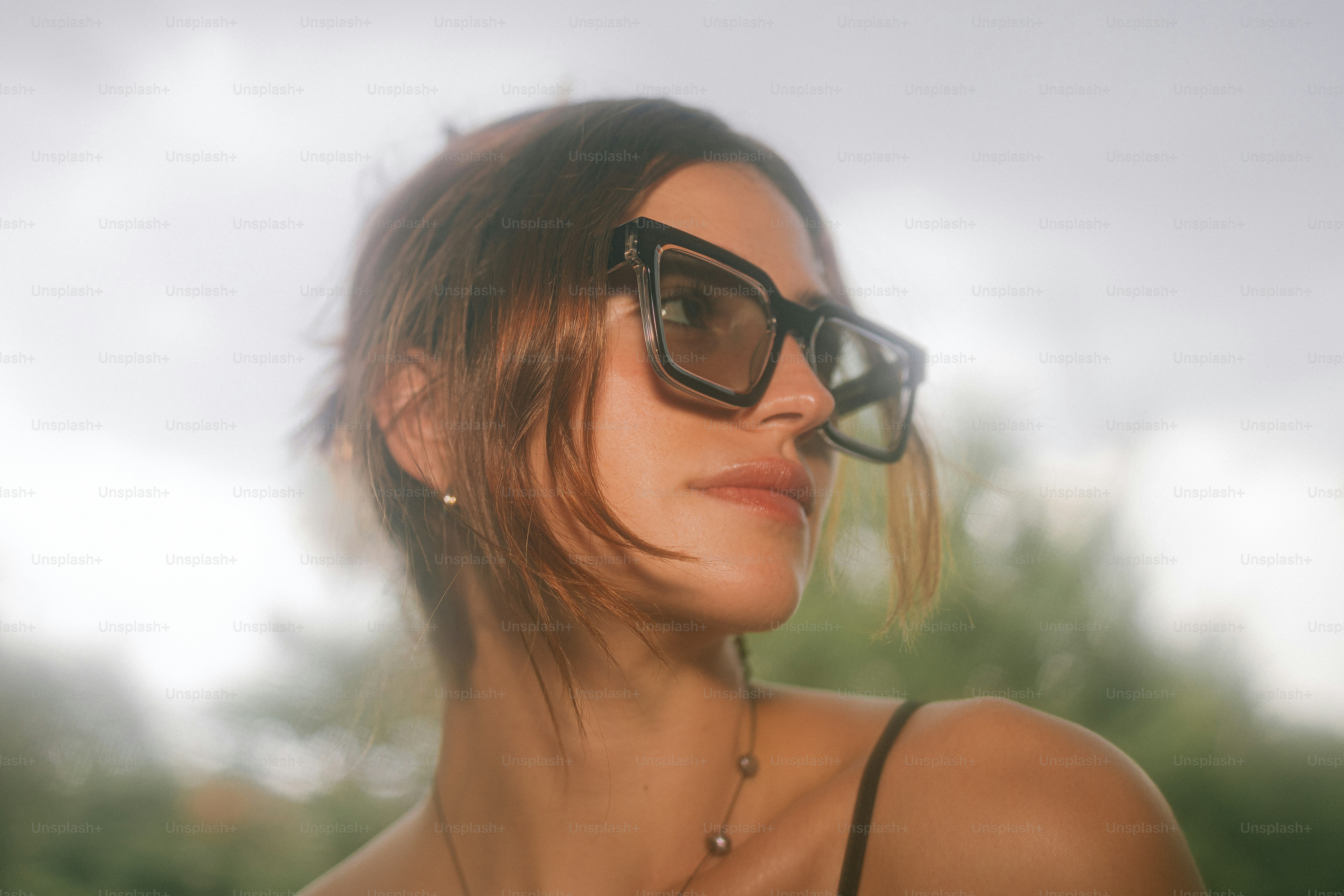 A woman poses, wearing glasses and a tank top - Photo on Unsplash+