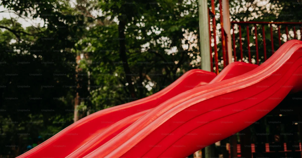 Red slide in the park with a blurry background. photo – Joy Image on ...