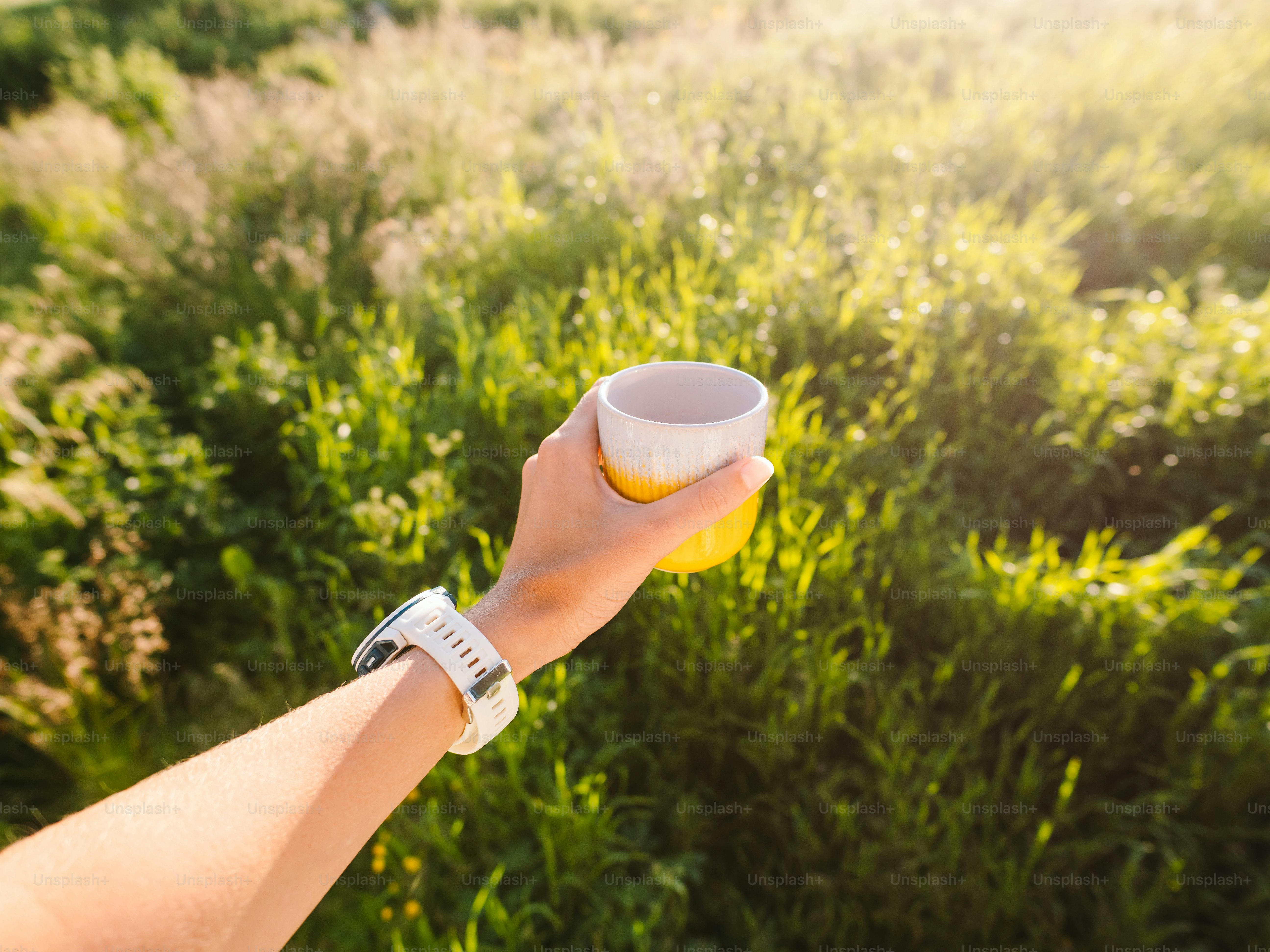Holding a cup while enjoying the sunny outdoors.