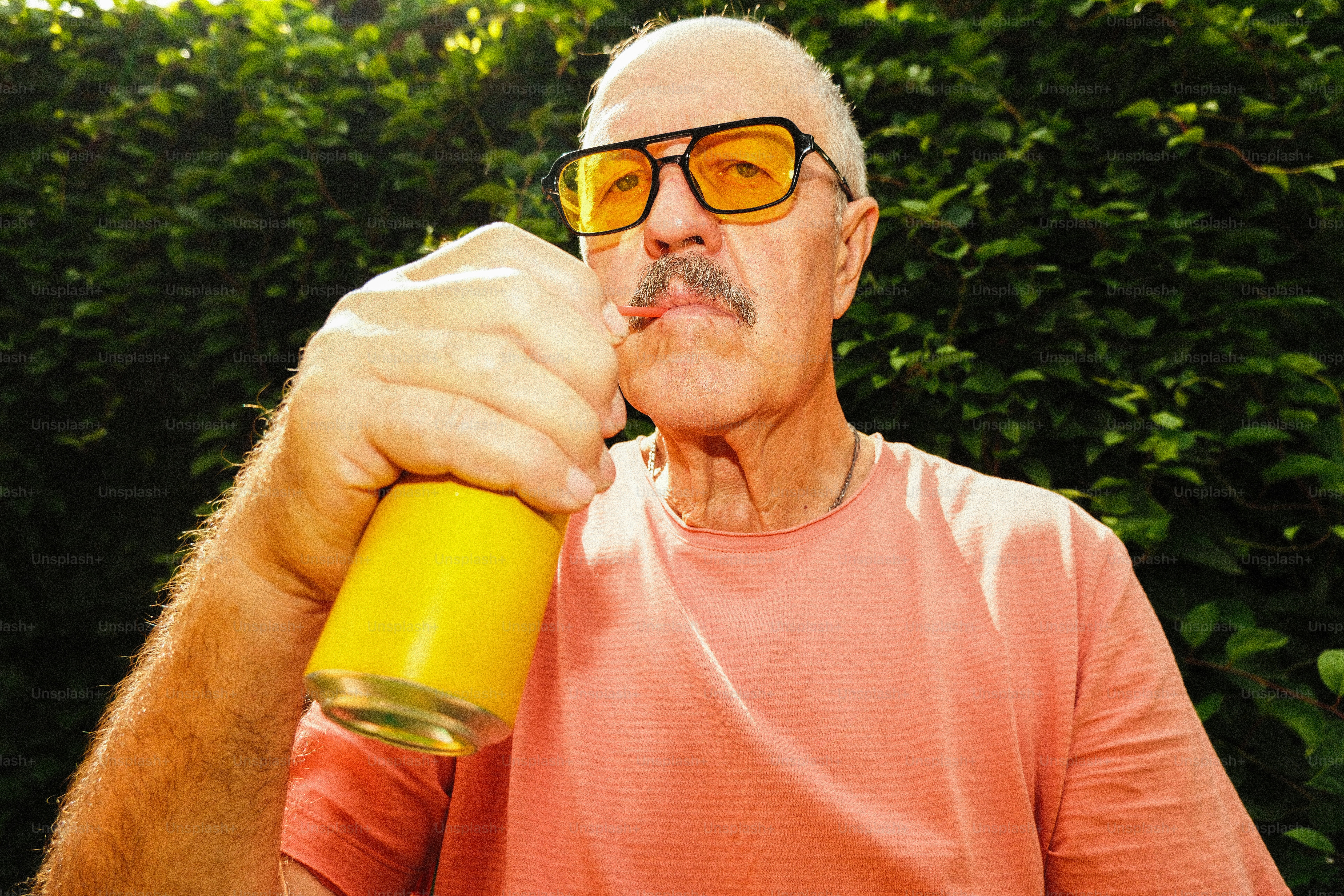 Mann mit Brille trinkt aus einer gelben Dose.