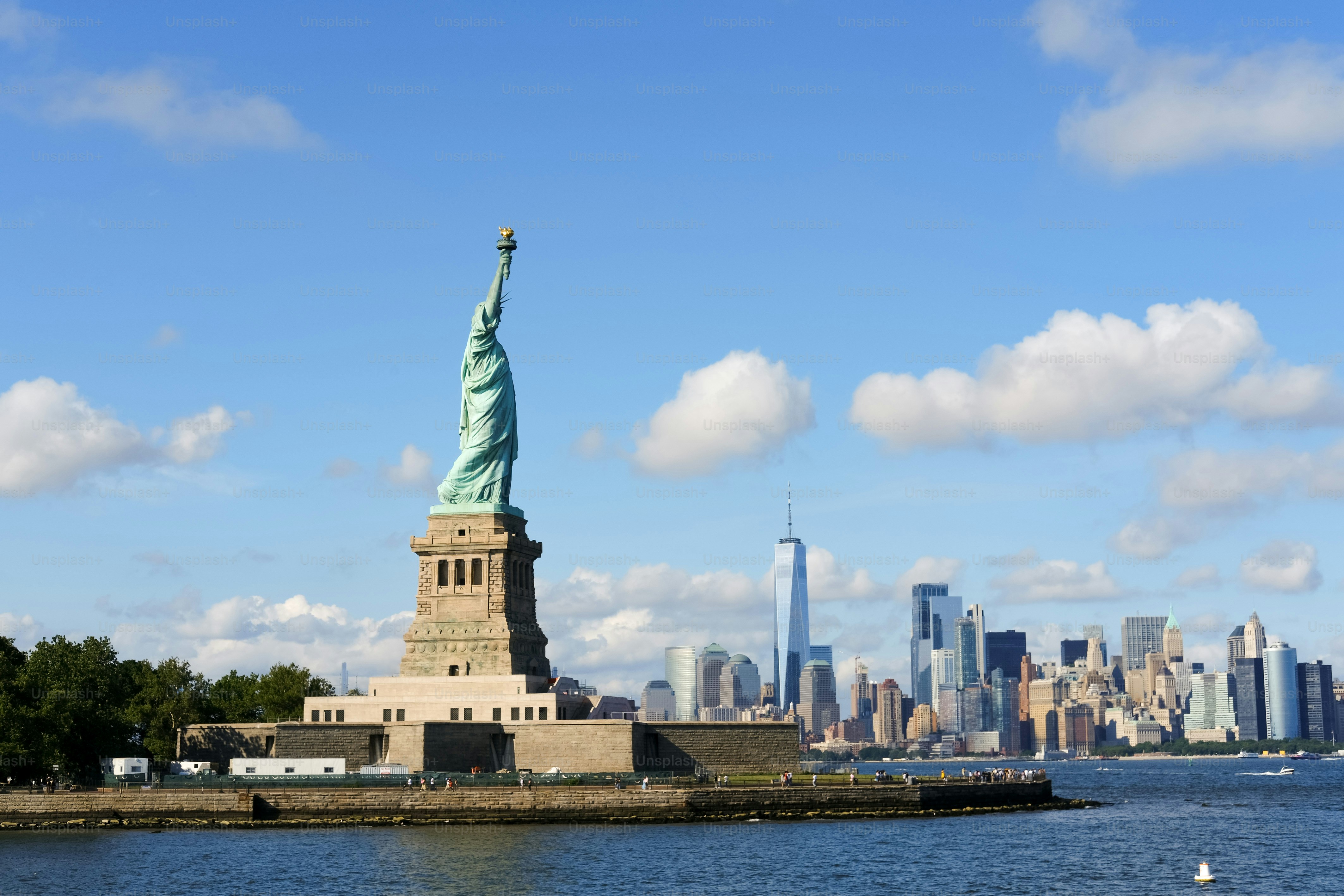 The statue of liberty stands before the new york city skyline.