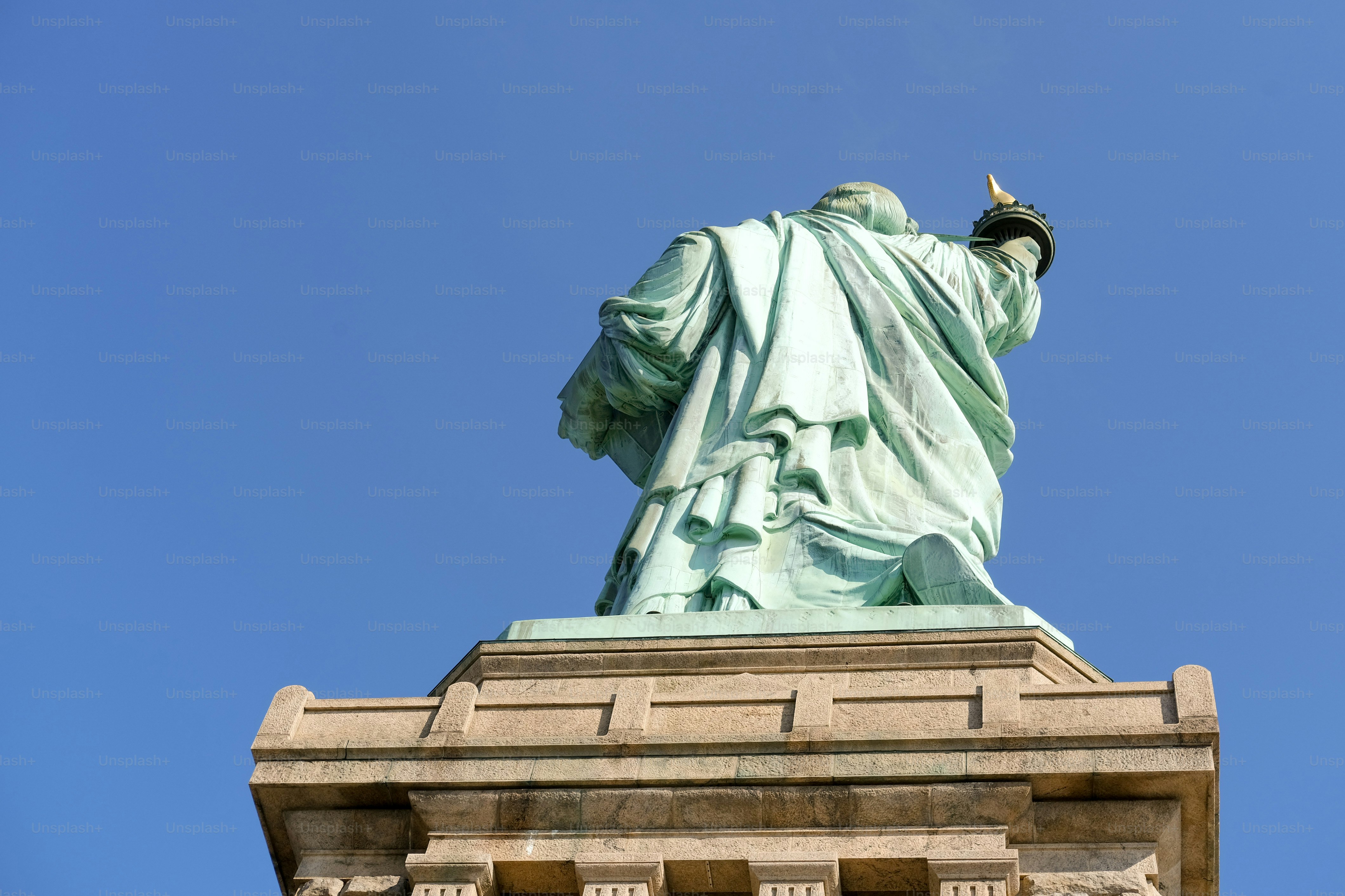 Die Freiheitsstatue steht vor blauem Himmel.