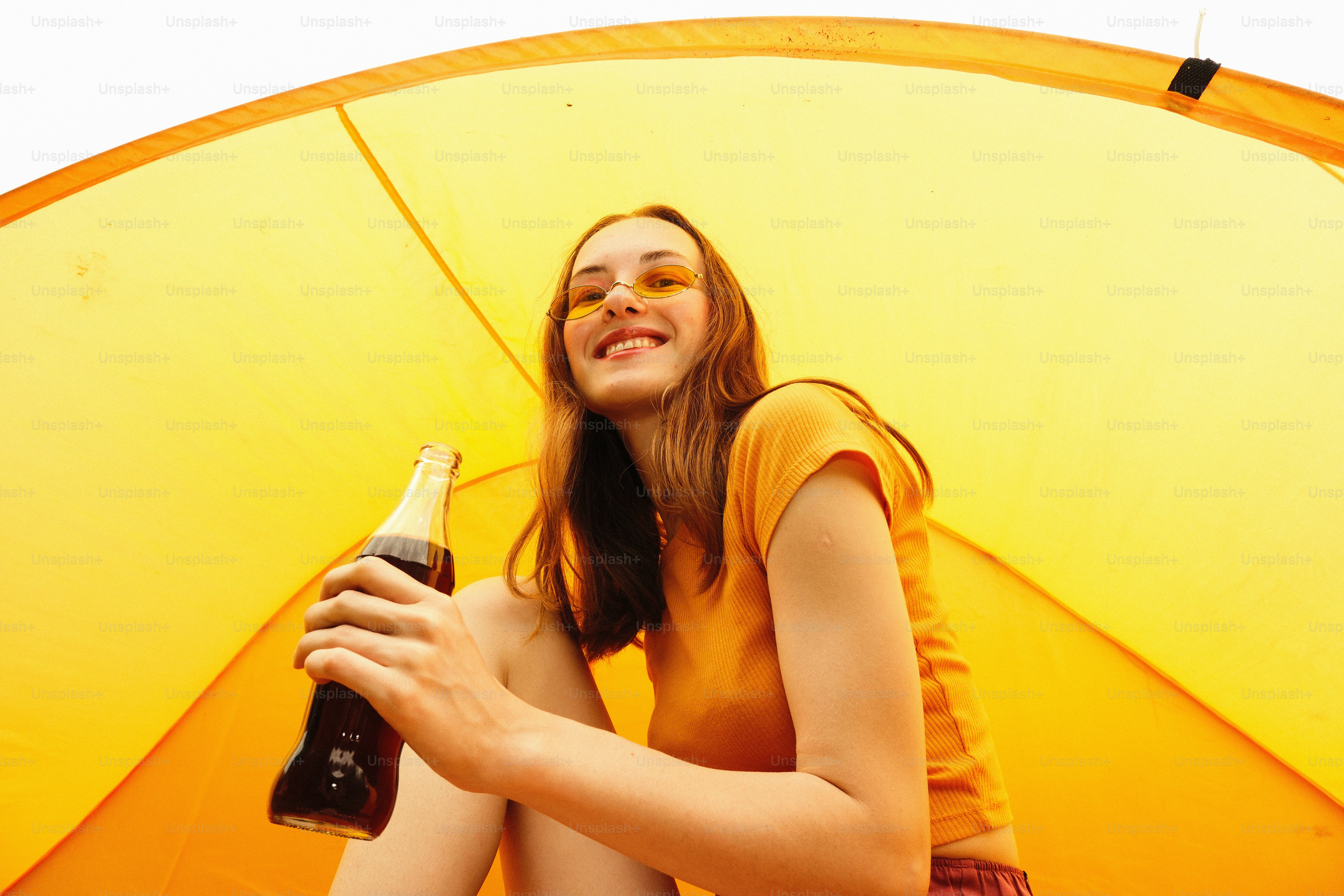 A woman smiles while holding a drink.