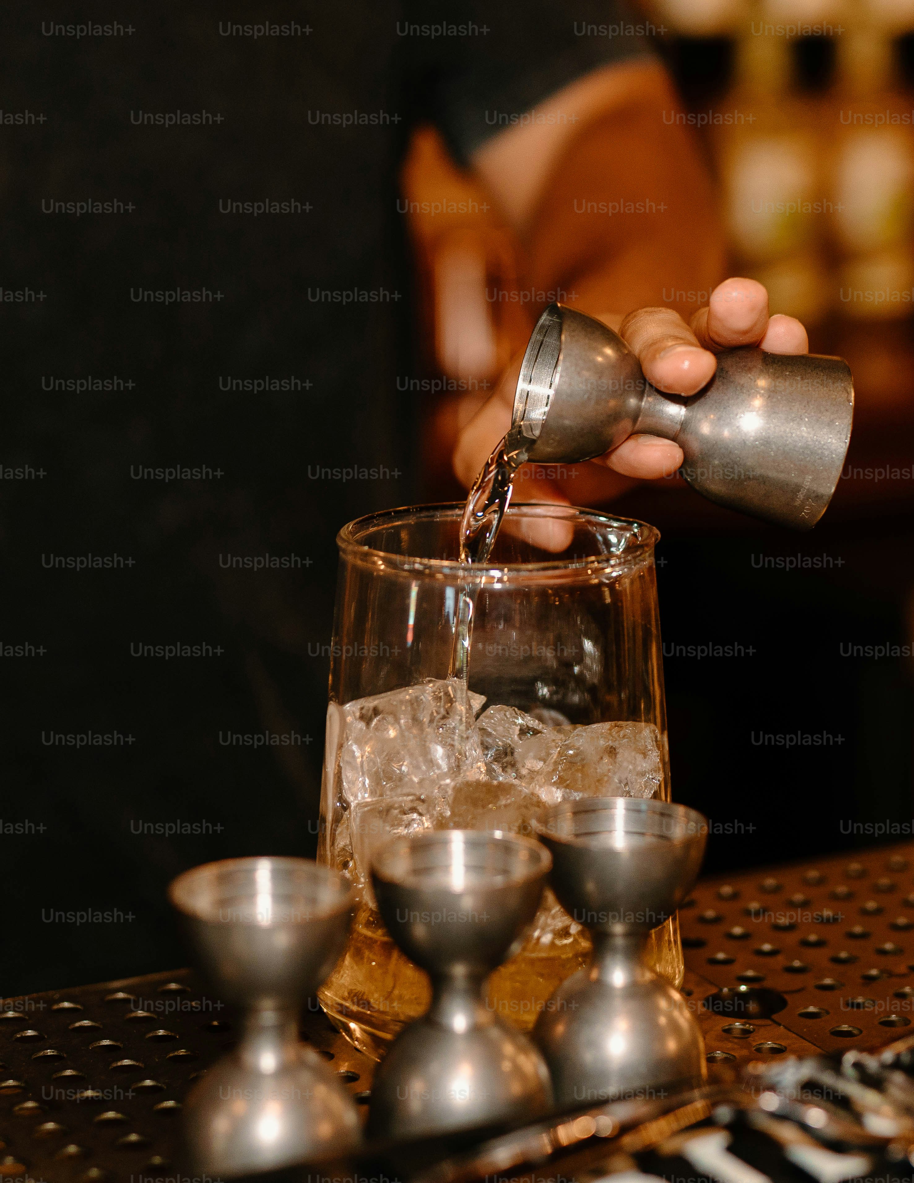 Bartender is pouring a drink into a glass.