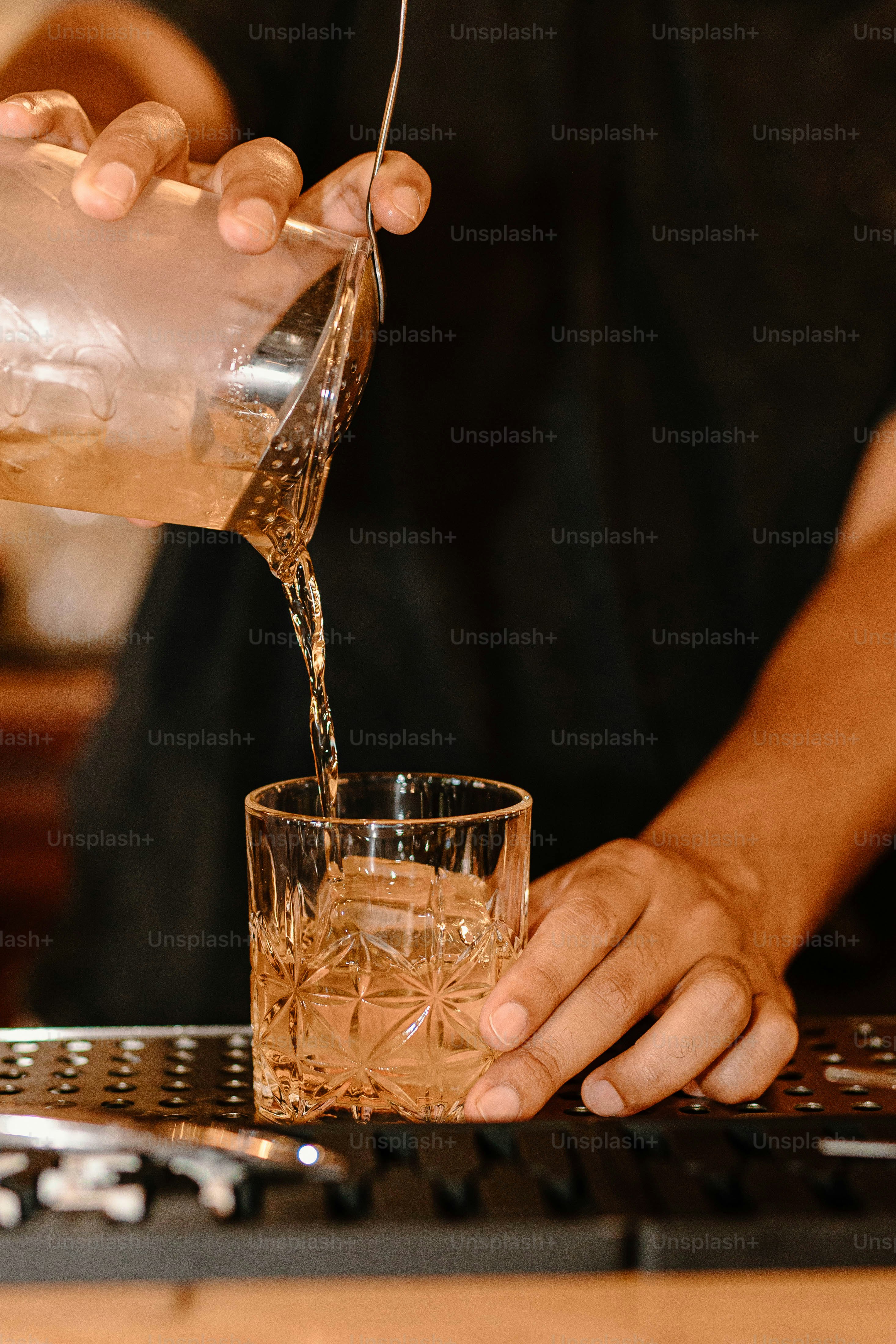 A bartender pours a drink into a glass.
