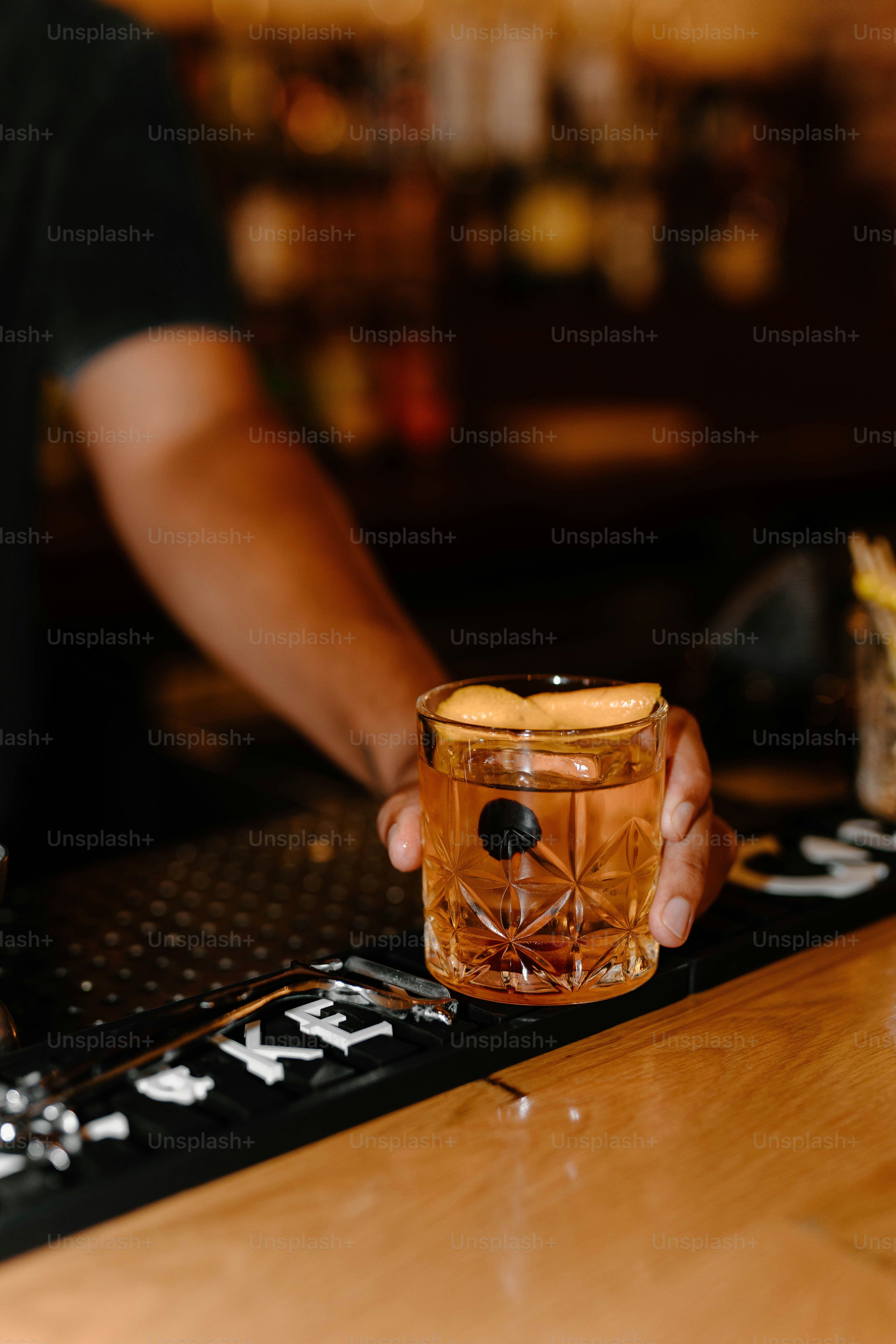 Bartender is holding a cocktail at the bar.