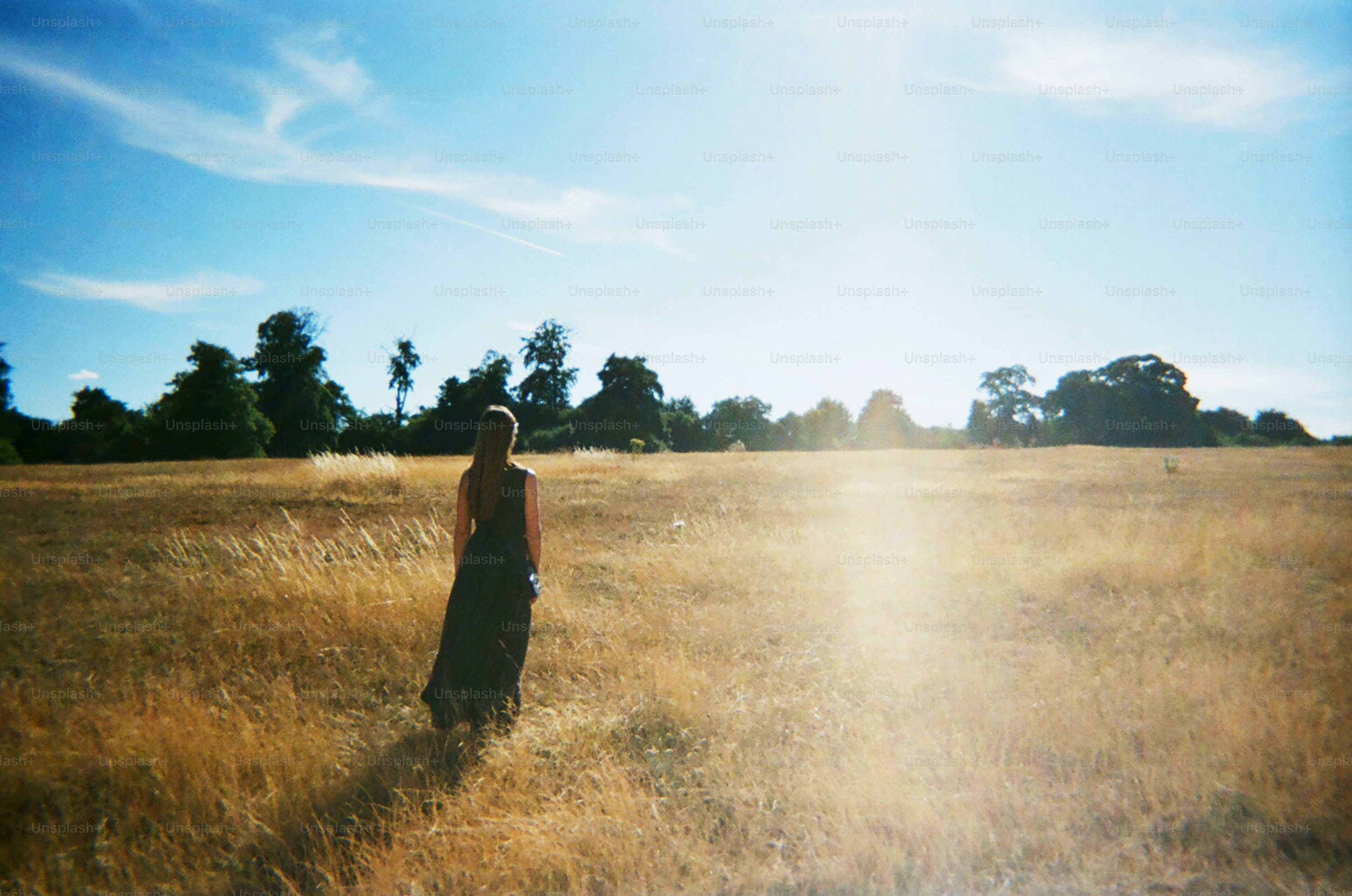 Une femme se tient dans un champ par une journée ensoleillée.