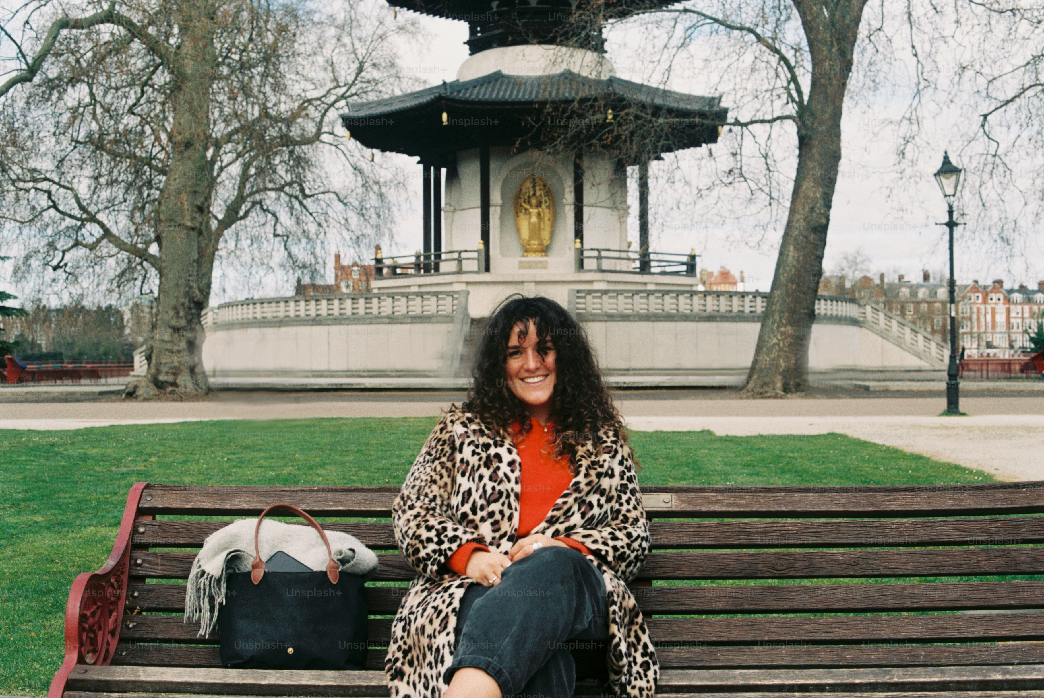 Une femme sourit sur un banc dans un parc.