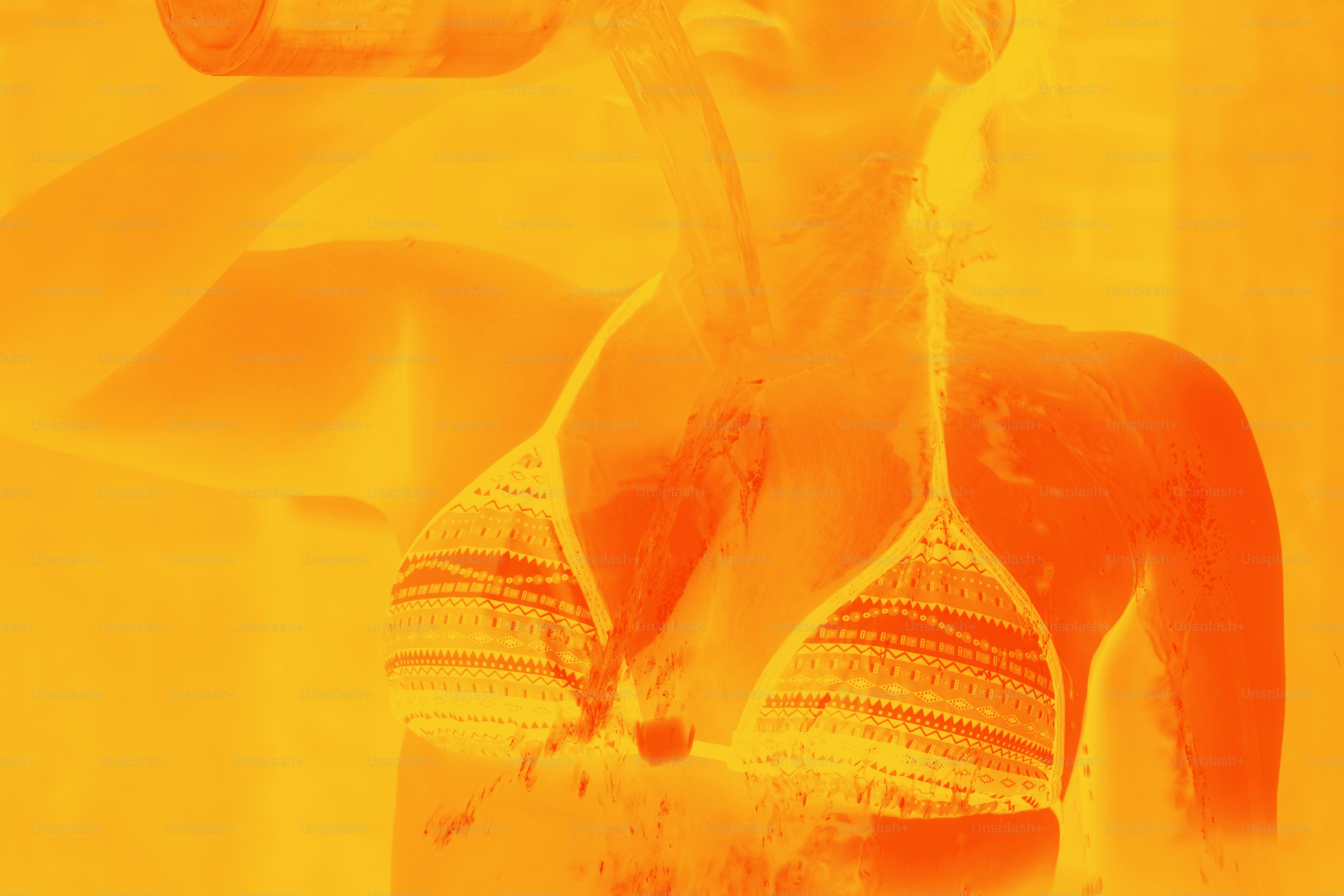 Woman in a bikini drinks from a bottle.
